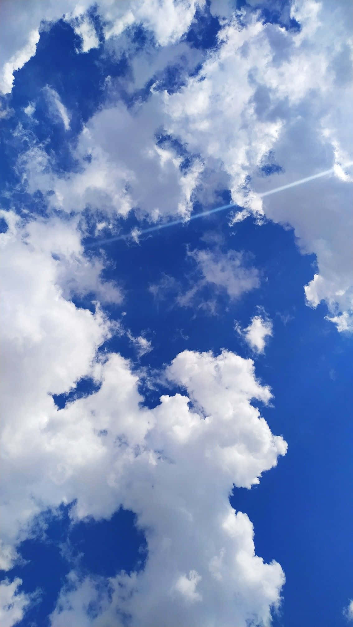 唯美雲朵 桌布 壁紙 — 充滿蓬鬆白雲的鮮豔藍天，一道明亮的陽光穿透而過。