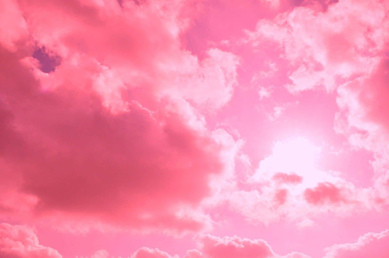 Pink Cloud 桌布 壁紙 — 充滿蓬鬆雲朵的鮮豔粉紅色天空，明亮的陽光穿透雲層。