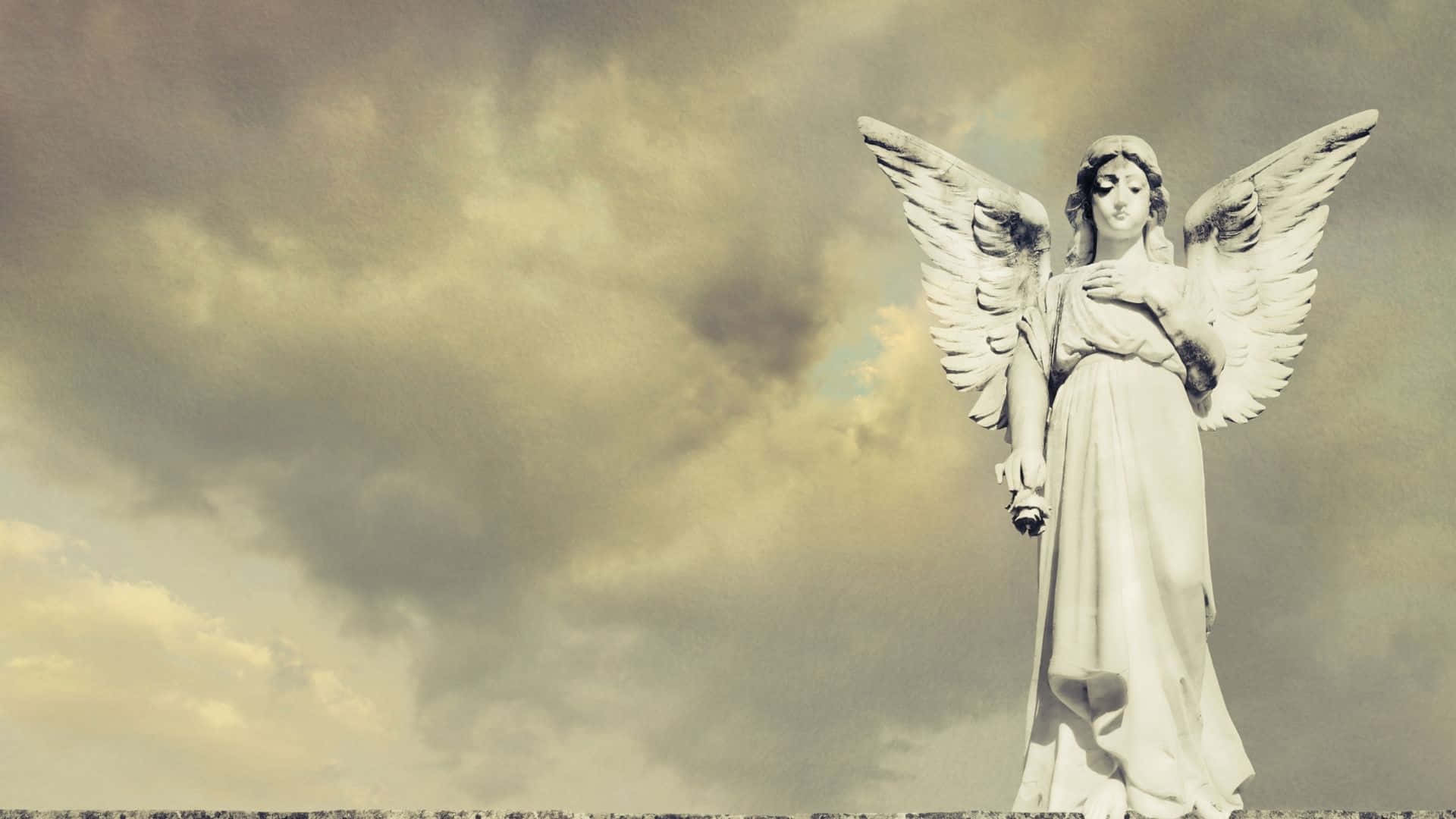 多雲天空下展開翅膀的石天使雕像