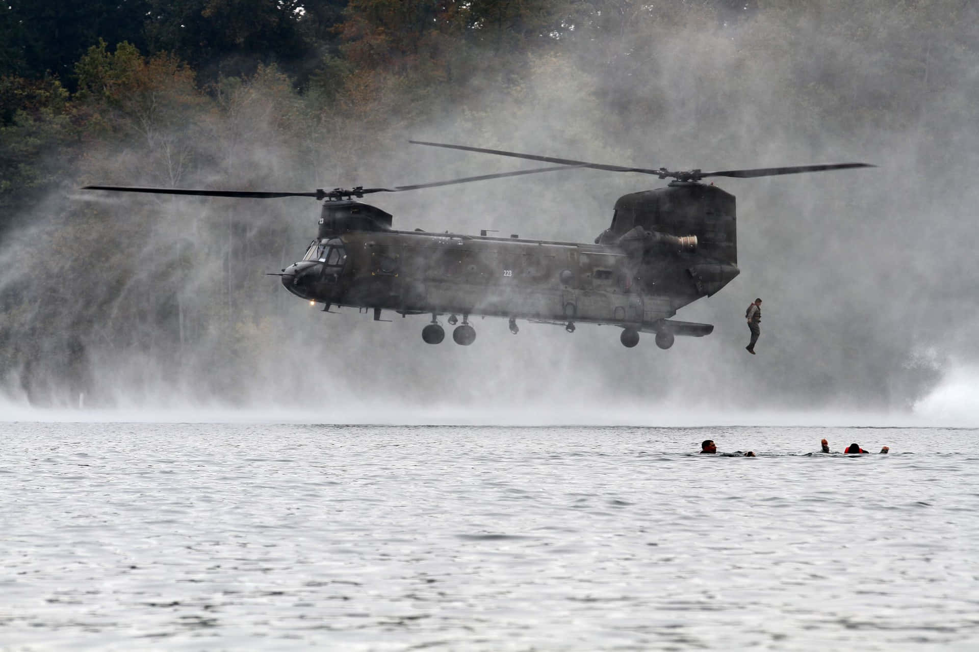 軍用直升機在水面上盤旋，士兵游繩下降，其他士兵游泳。