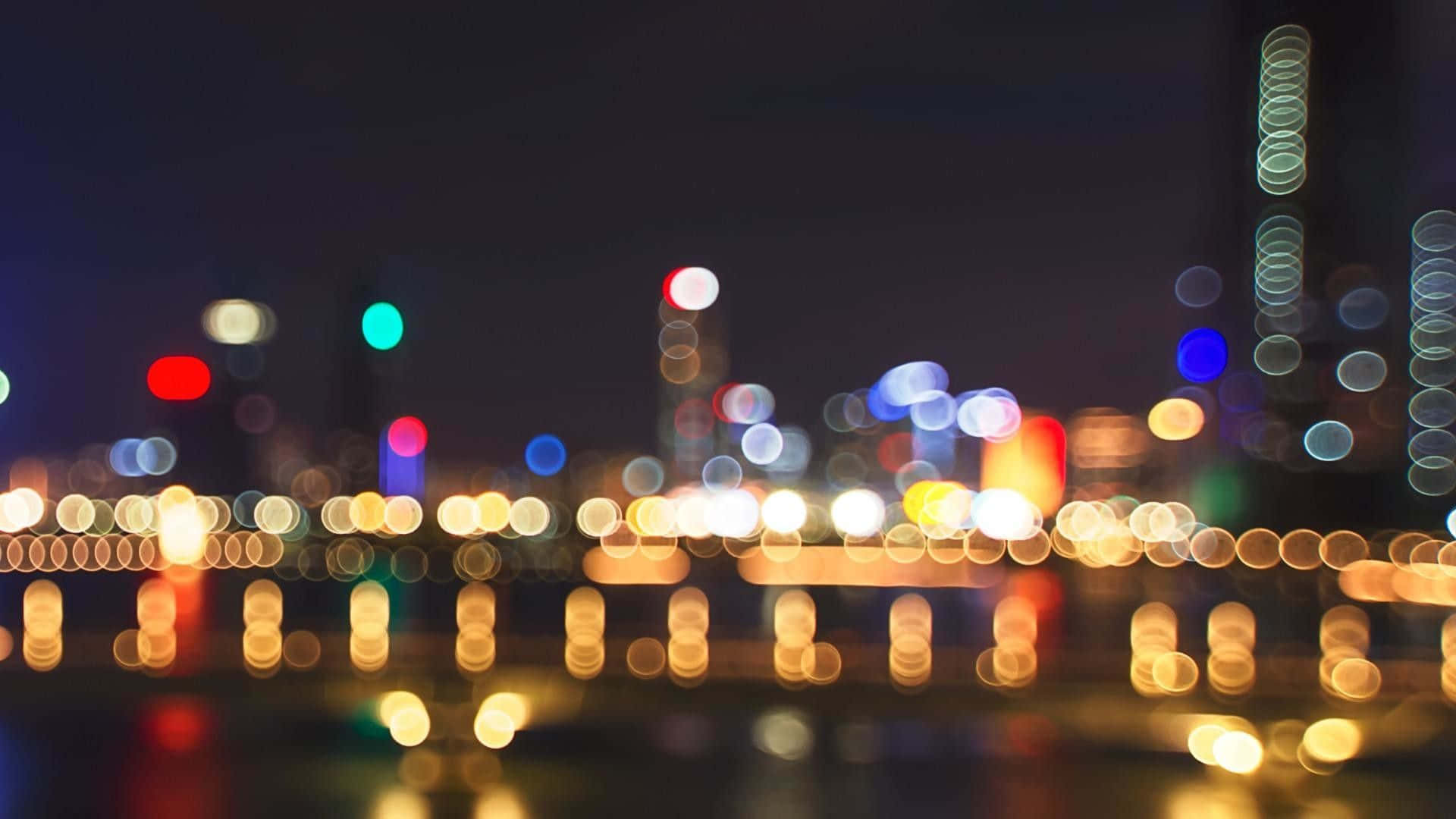 夜晚的城市燈光模糊成發光球體，倒映在水面上。