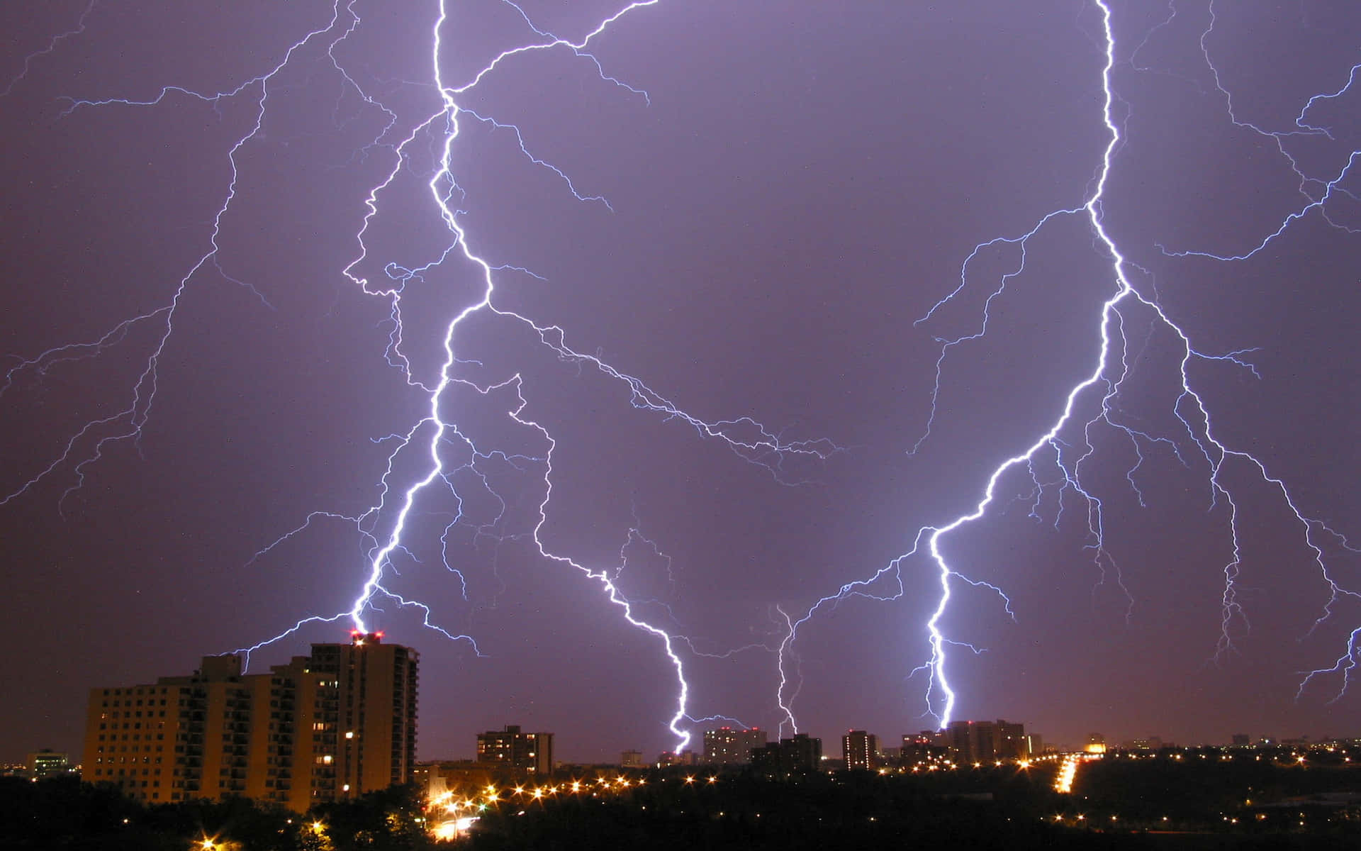 夜間城市上空強烈的閃電，下方是明亮的建築物。