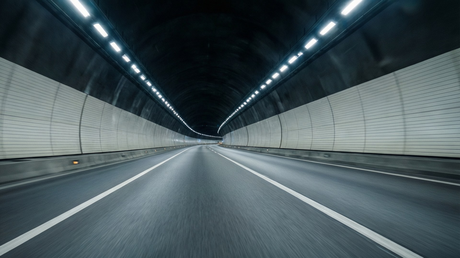 一條長隧道，白色牆壁和頭頂燈光在黑暗的道路上。