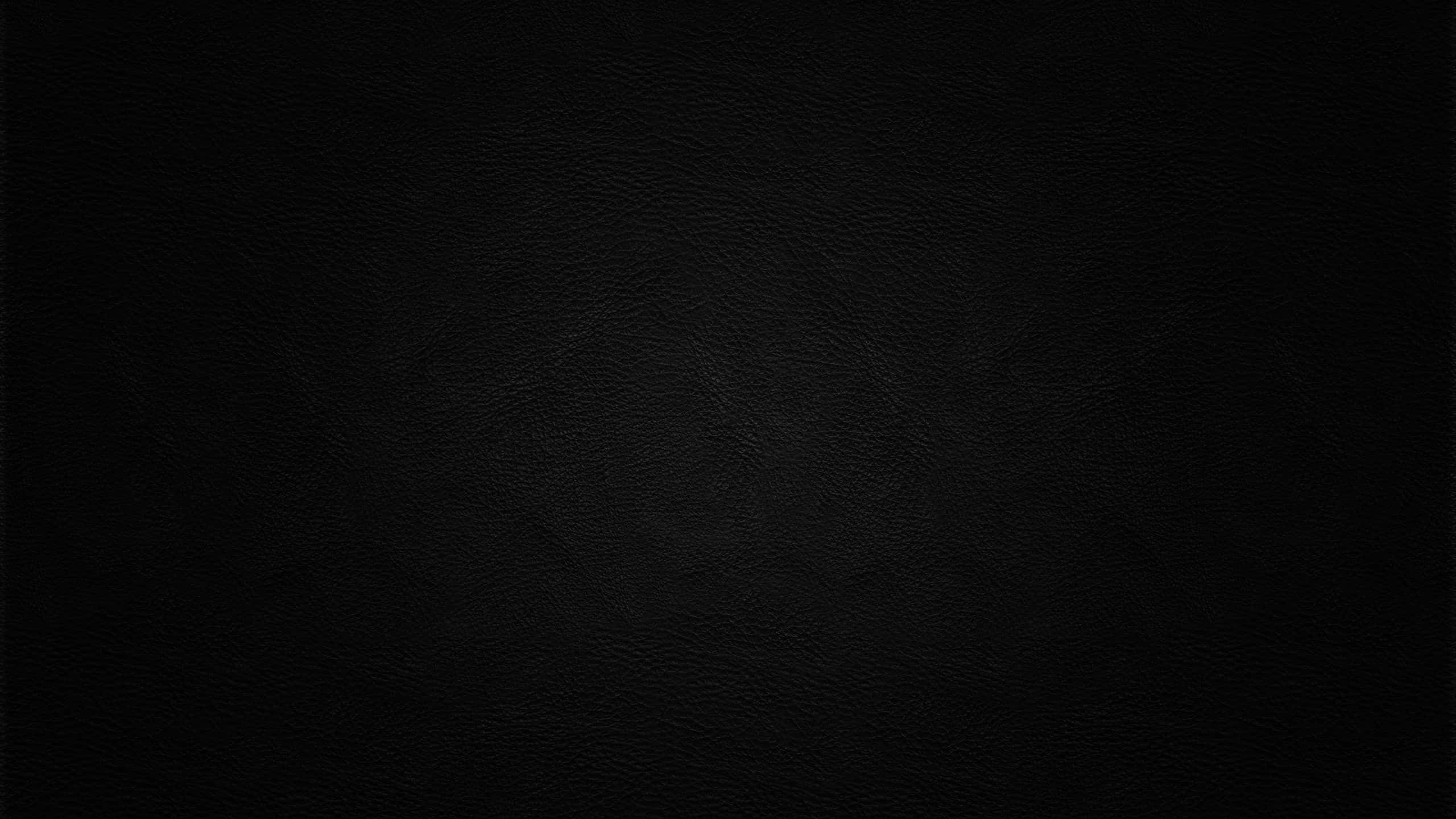 光滑黑色皮革紋理 壁紙 — 柔軟燈光下光滑黑色皮革表面帶有細微粒面紋理的近距離特寫。