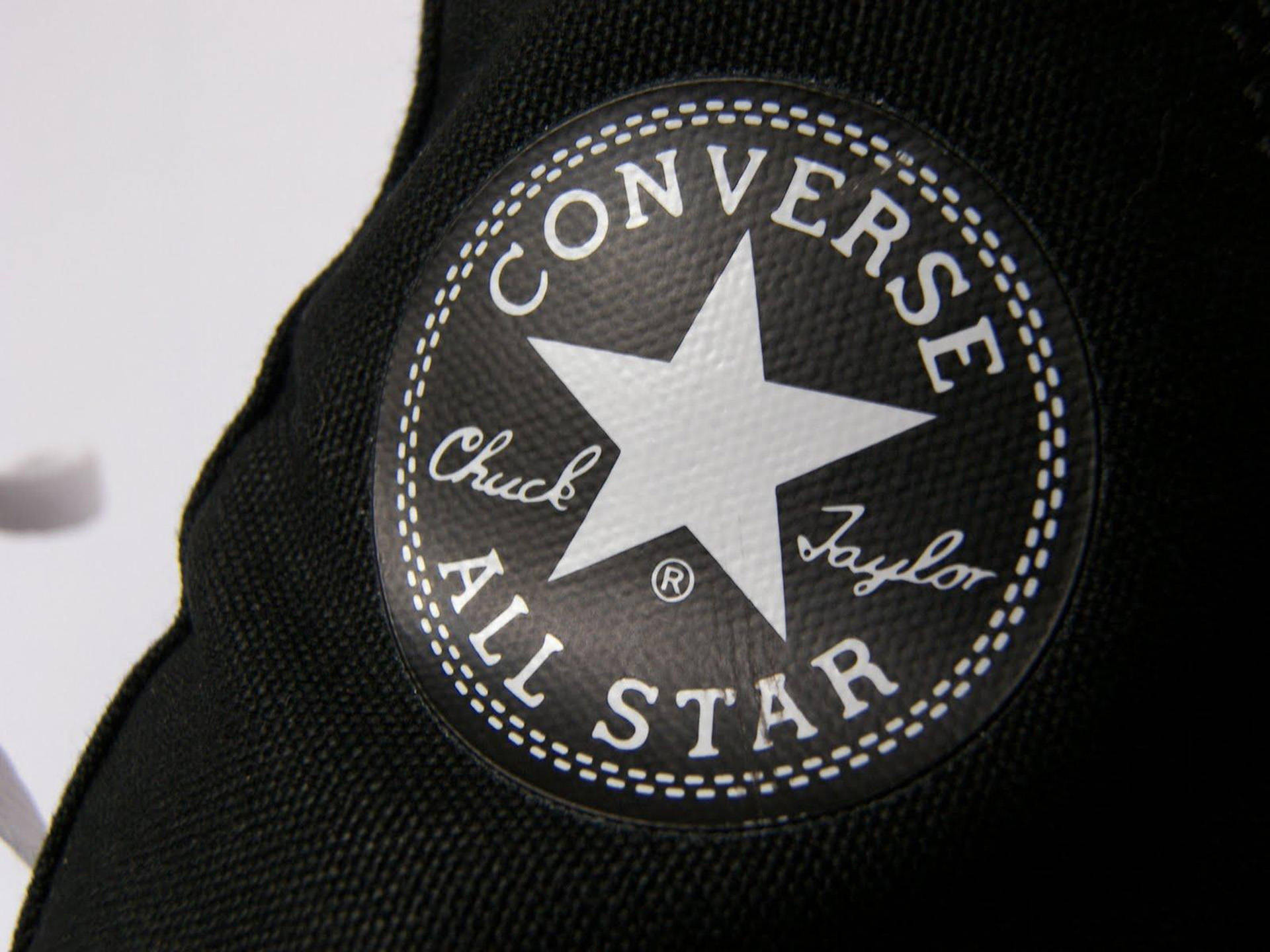光澤All-Star匡威標誌 壁紙 — 黑色Converse Chuck Taylor All Star標誌布章特寫，帶有白色縫線和星星，位於帆布上。