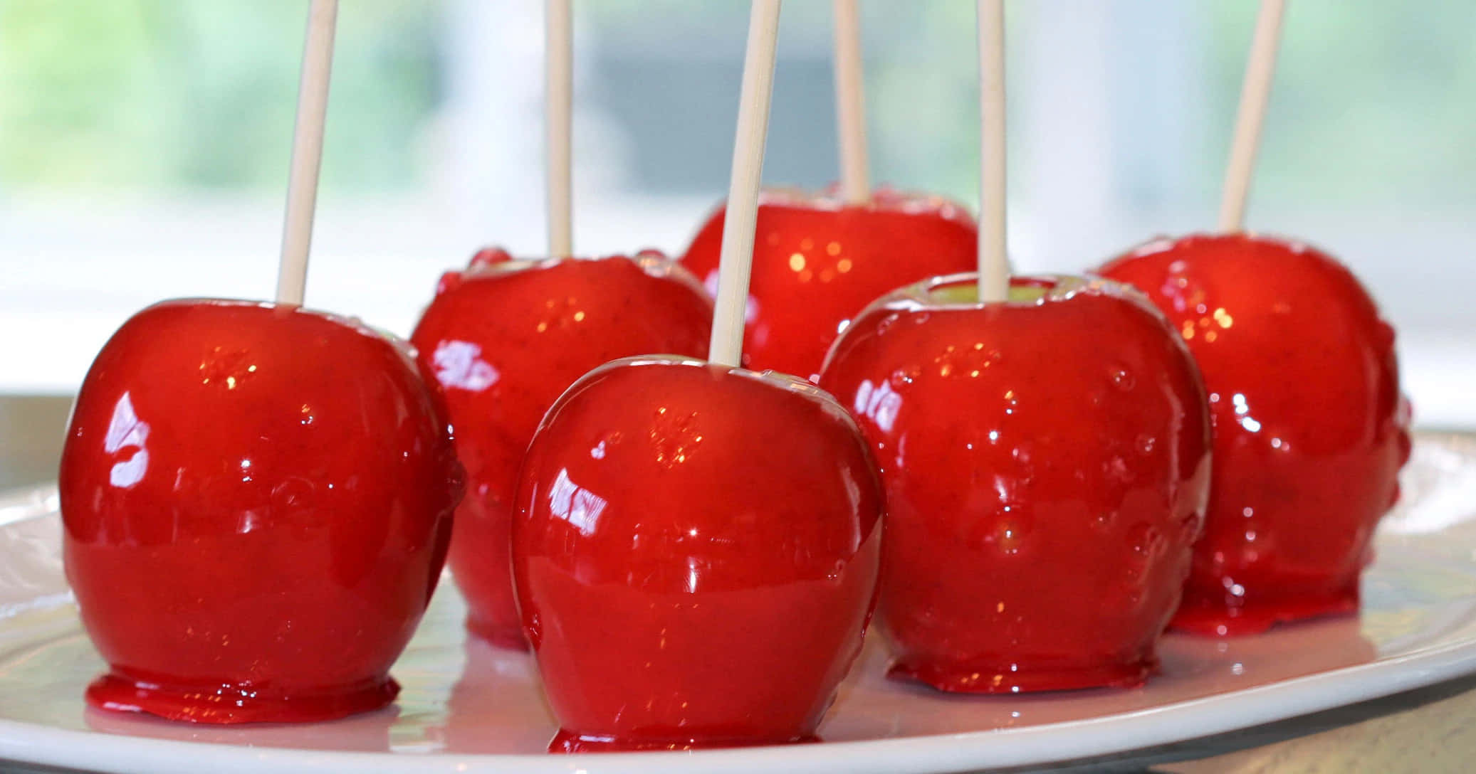Candy Apples 桌布 壁紙 — 光澤的紅色糖蘋果串在白色碟上排列，柔和自然光凸顯其糖衣光澤。