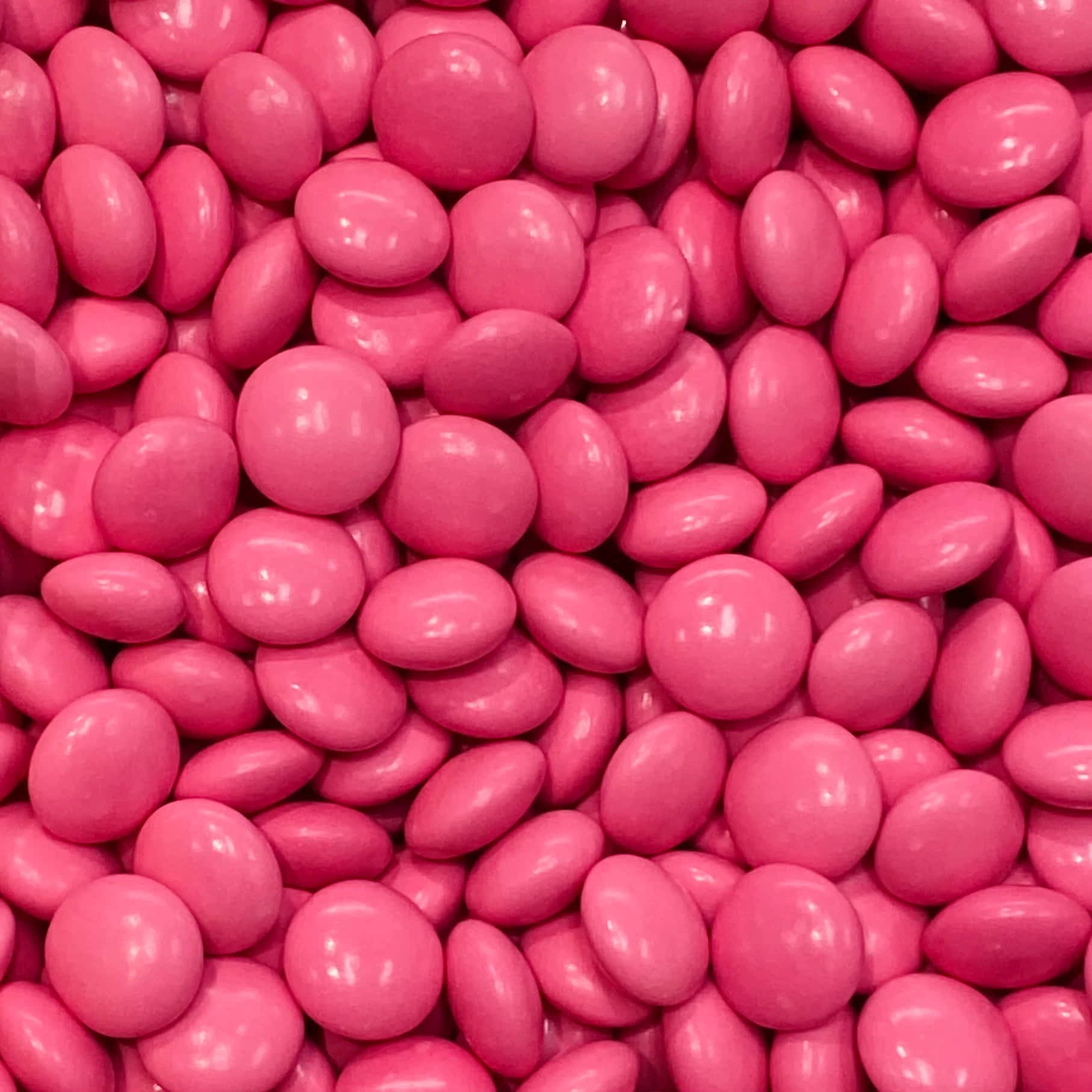 Pink Candy 桌布 壁紙 — 光澤粉紅色糖果塗層朱古力緊密堆疊的特寫，帶有反射高光。