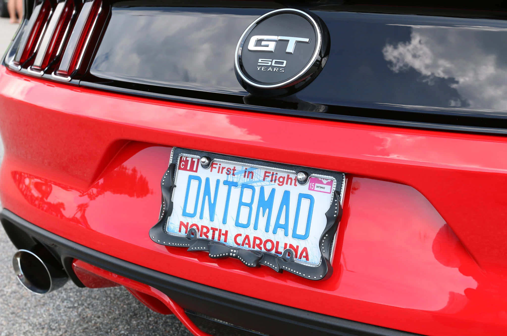 Car License Plate 桌布 壁紙 — 光澤紅色Ford Mustang GT 50 Years徽章和定制北卡羅來納州車牌的近距離特寫。