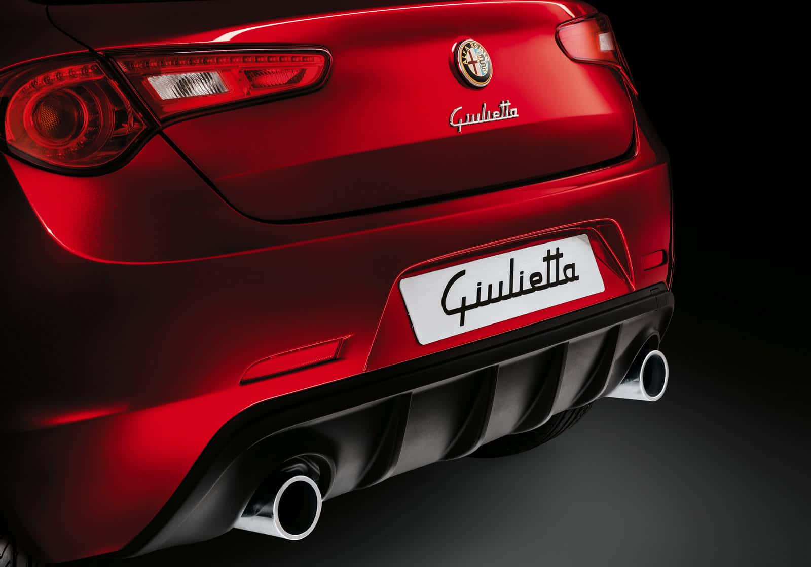 Alfa Romeo Giulietta 桌布 壁紙 — 光澤紅色愛快羅密歐Giulietta後視圖，展示雙排氣管和時尚尾燈，背景為深色攝影棚。