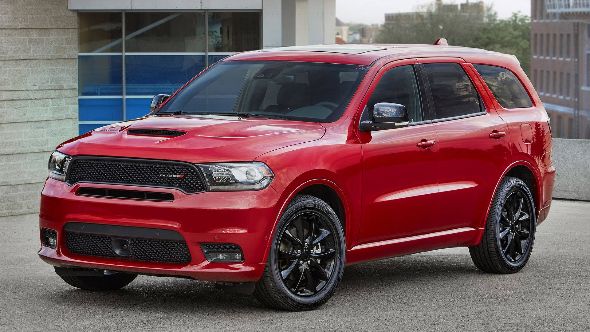 光澤紅色杜蘭戈停於門前 壁紙 — 一輛亮紅色Dodge Durango SRT SUV配黑色輪圈，停泊在現代建築附近的瀝青路面上。