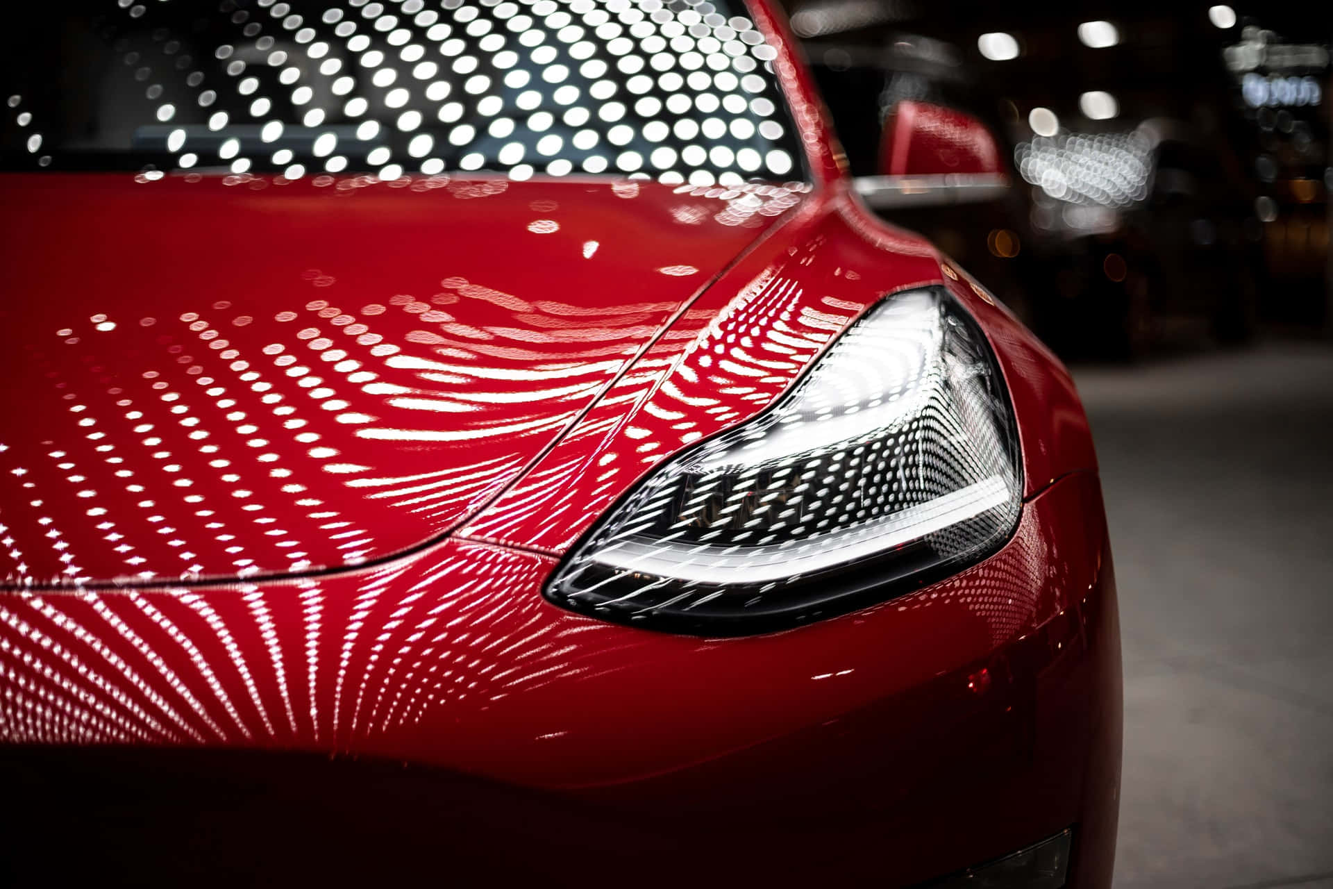 tesla 桌布 壁紙 — 光澤紅色車頭的特寫，引擎蓋和時尚車頭燈上呈現複雜的白色光線圖案。
