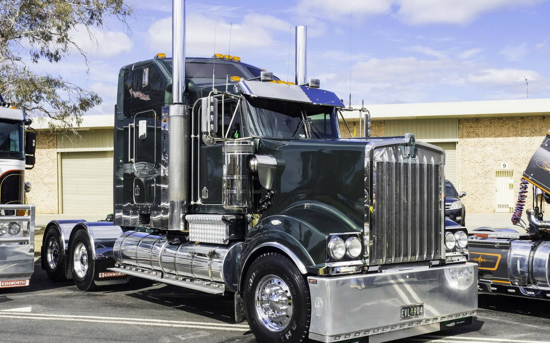 黑色Kenworth半掛卡車，帶有鍍鉻細節，在陽光明媚的日子停放在戶外。
