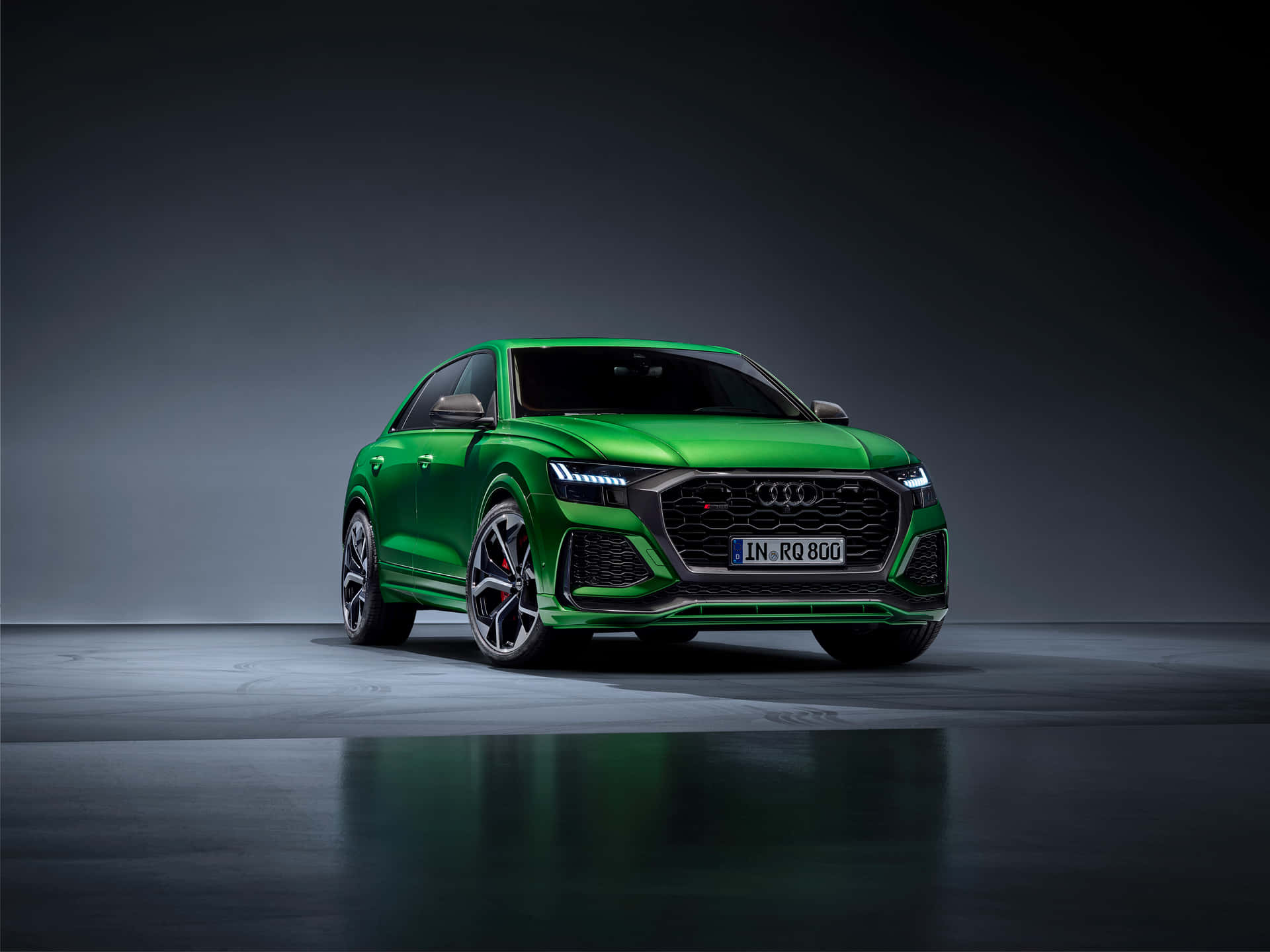 攝影棚中帶有反射地板和深色背景的充滿活力的綠色Audi SQ8 SUV。