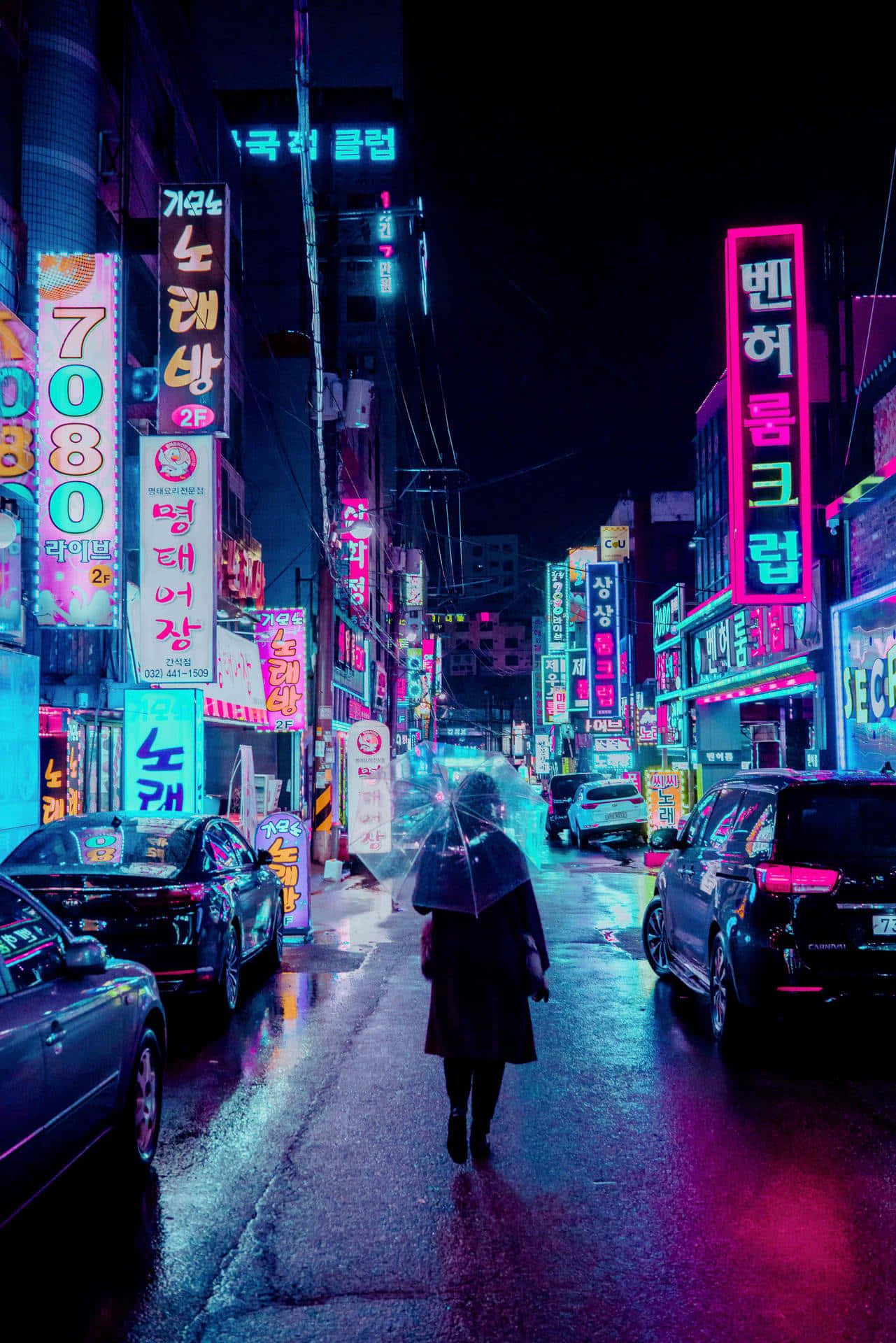 夜晚在霓虹燈照亮的雨街上撐傘行走的人。