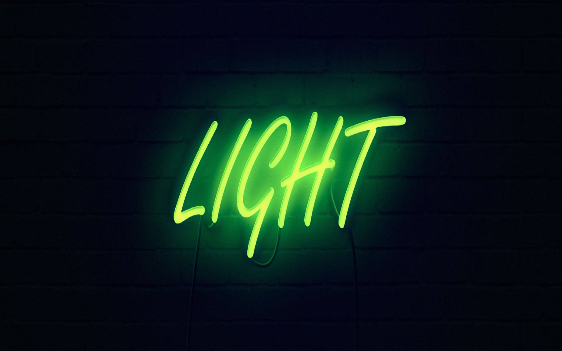 一個明亮的綠色霓虹燈牌，在深色磚牆上顯示 'LIGHT'。