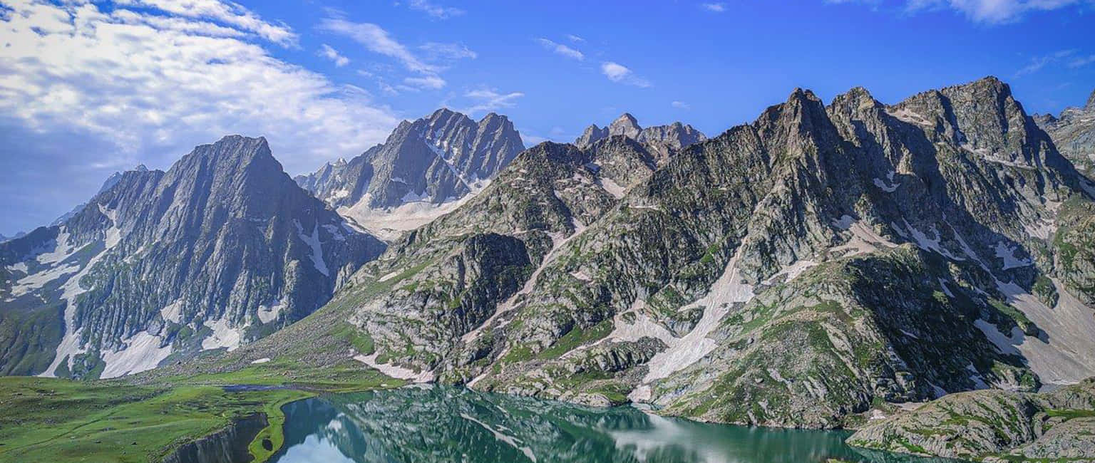 克什米爾維尚薩爾湖景 壁紙 — 寧靜的高山湖泊映照著鋸齒狀的雪峰，天空湛藍，白雲點綴。