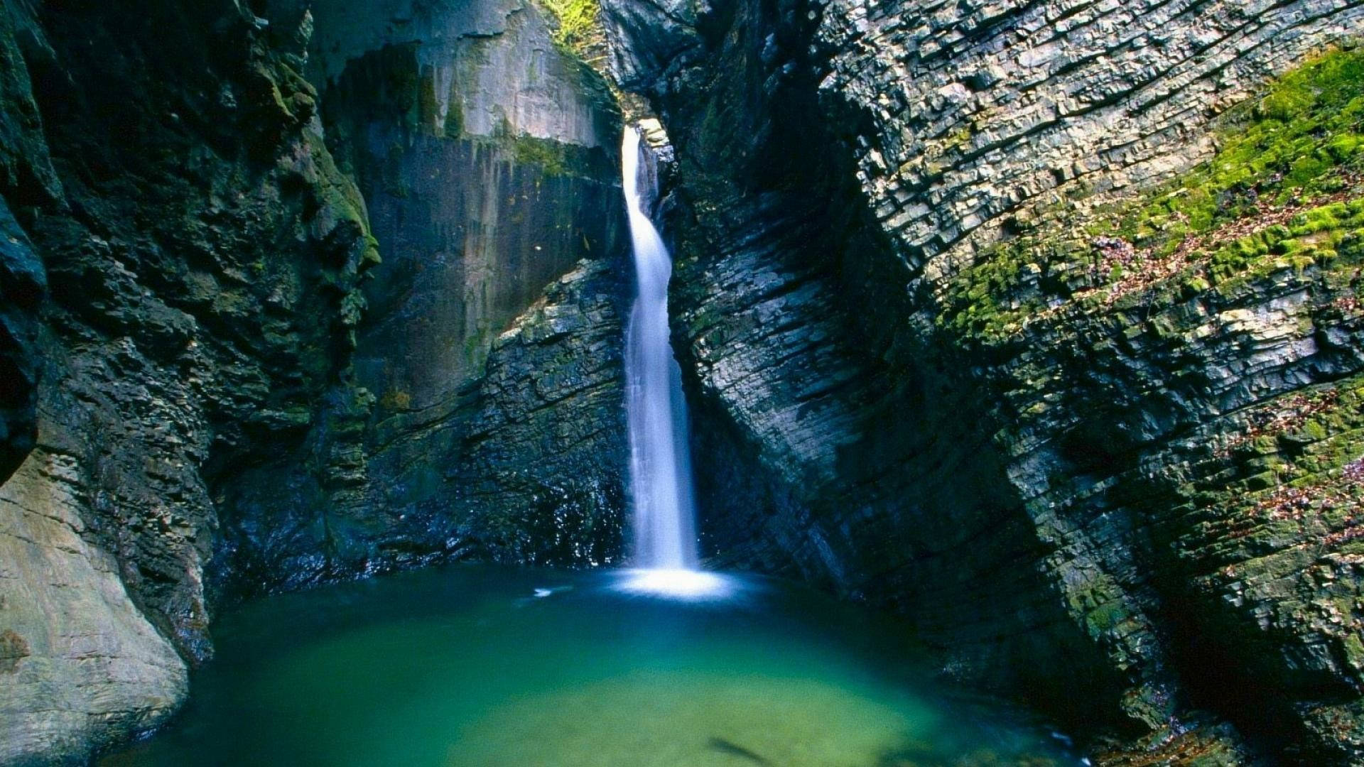 克扎克瀑布石灰岩洞自然風景 壁紙 — 一條狹窄的瀑布從崎嶇的懸崖傾瀉而下，流入下方寧靜的碧綠水池。