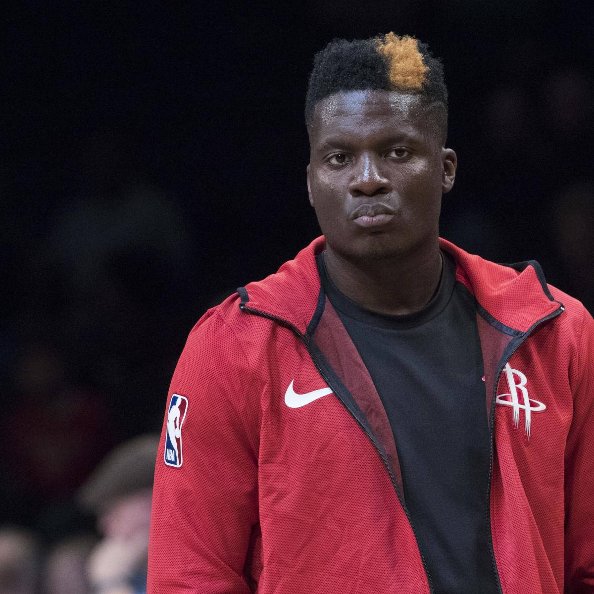 克林特·卡佩拉穿NBA夾克 壁紙 — 一名身穿侯斯頓火箭隊紅色外套的籃球運動員，頭髮上有一條大膽的橙色條紋，專注地凝視著。