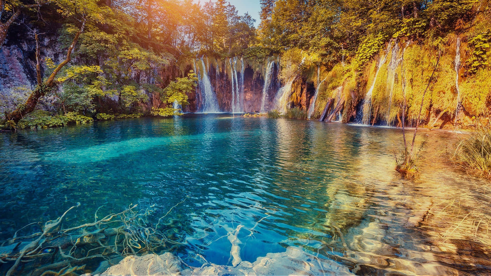 克羅地亞寧靜的藍湖 壁紙 — 陽光在碧綠的水面上閃爍，層疊的瀑布傾瀉入寧靜的森林水池。