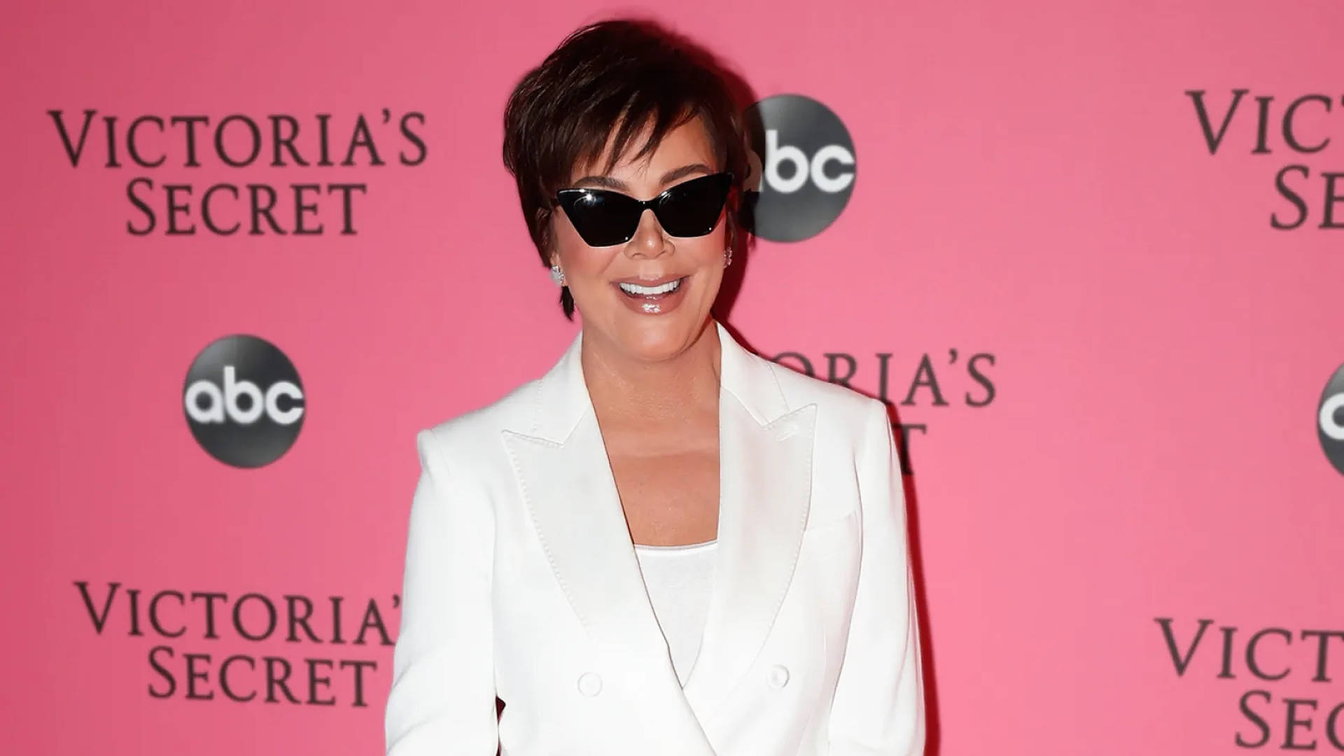 Kris Jenner 在Victoria's Secret活動中戴著太陽眼鏡和白色西裝外套。