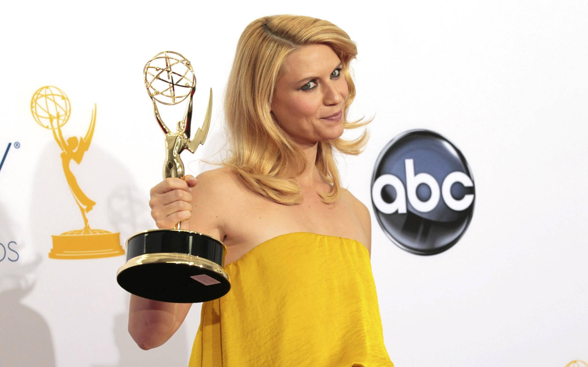 身穿黃色連衣裙的女子在ABC活動中手持艾美獎。