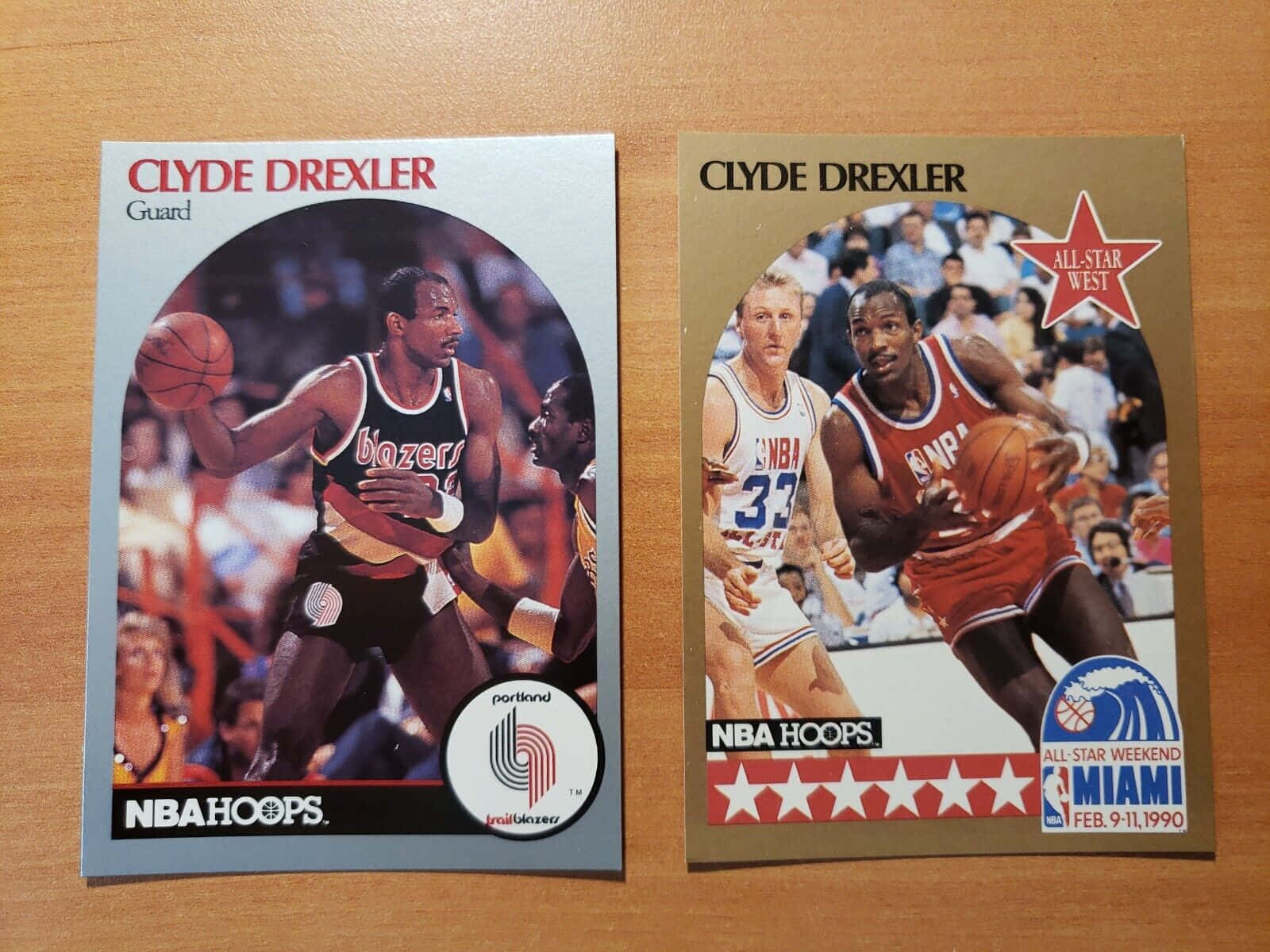 克萊德·德雷克斯勒 NBA Hoops 雜誌封面 壁紙 — 兩張復古NBA Hoops交易卡，展示Clyde Drexler在木桌上嘅動作姿勢。