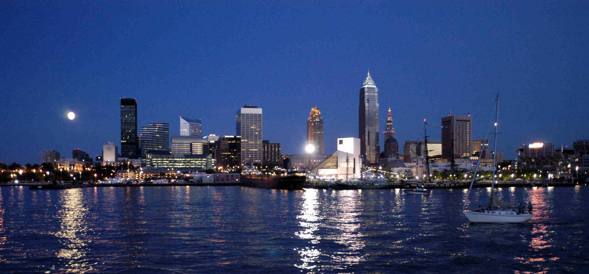 黃昏時分水面上的帆船，城市天際線和月光倒影