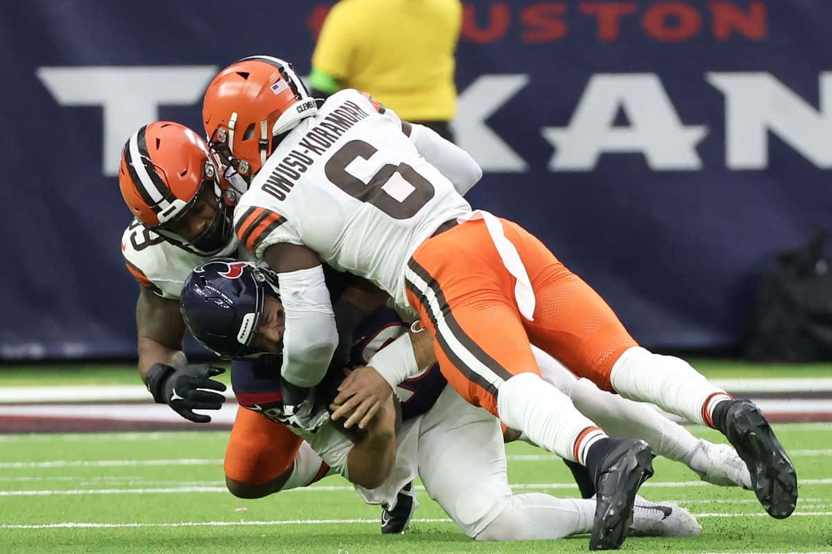  壁紙 — 克里夫蘭布朗隊60號球員在激烈的NFL比賽中擒抱侯斯頓德州人隊四分衛。