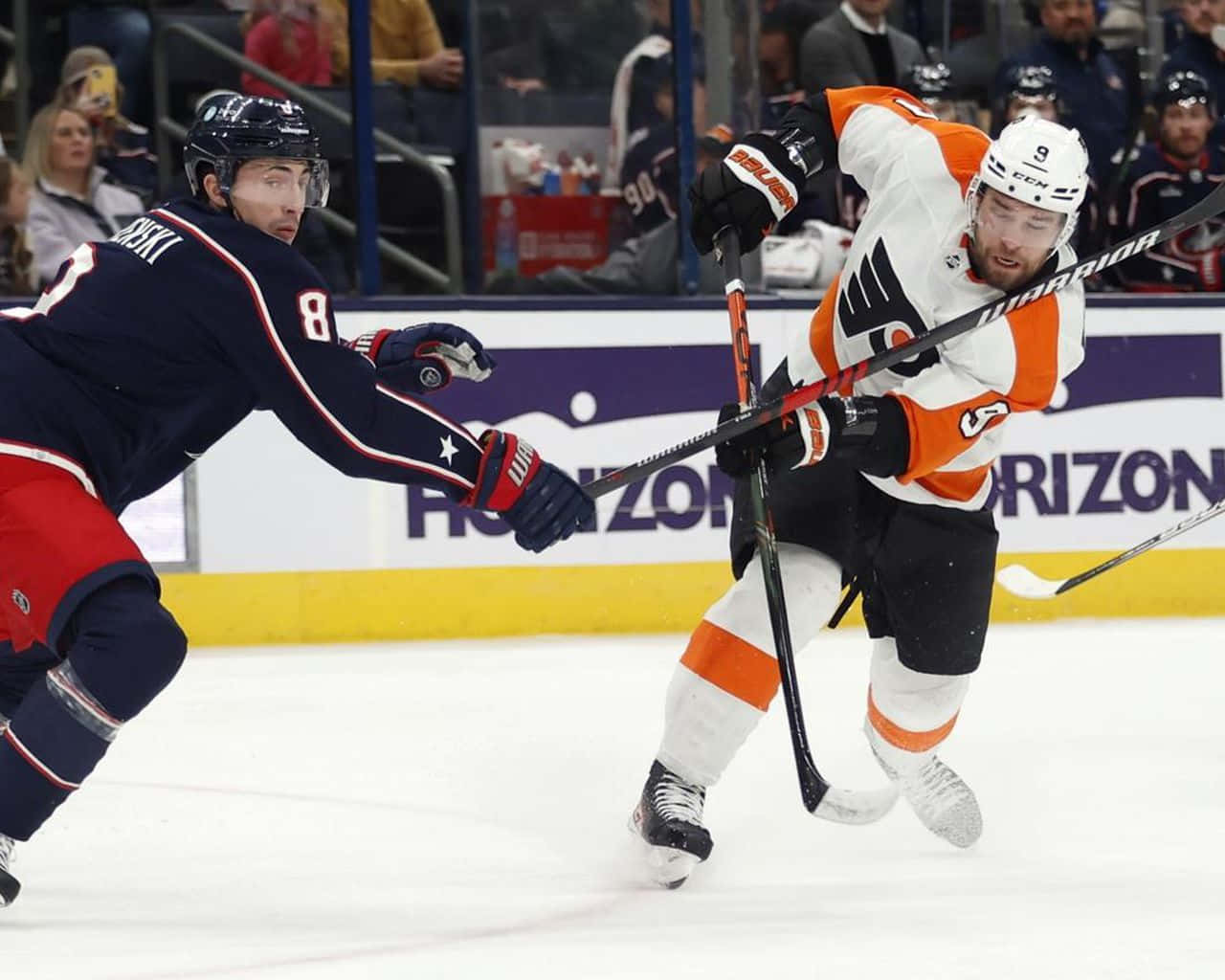 兩名曲棍球運動員在比賽中於冰上爭奪控球權。
