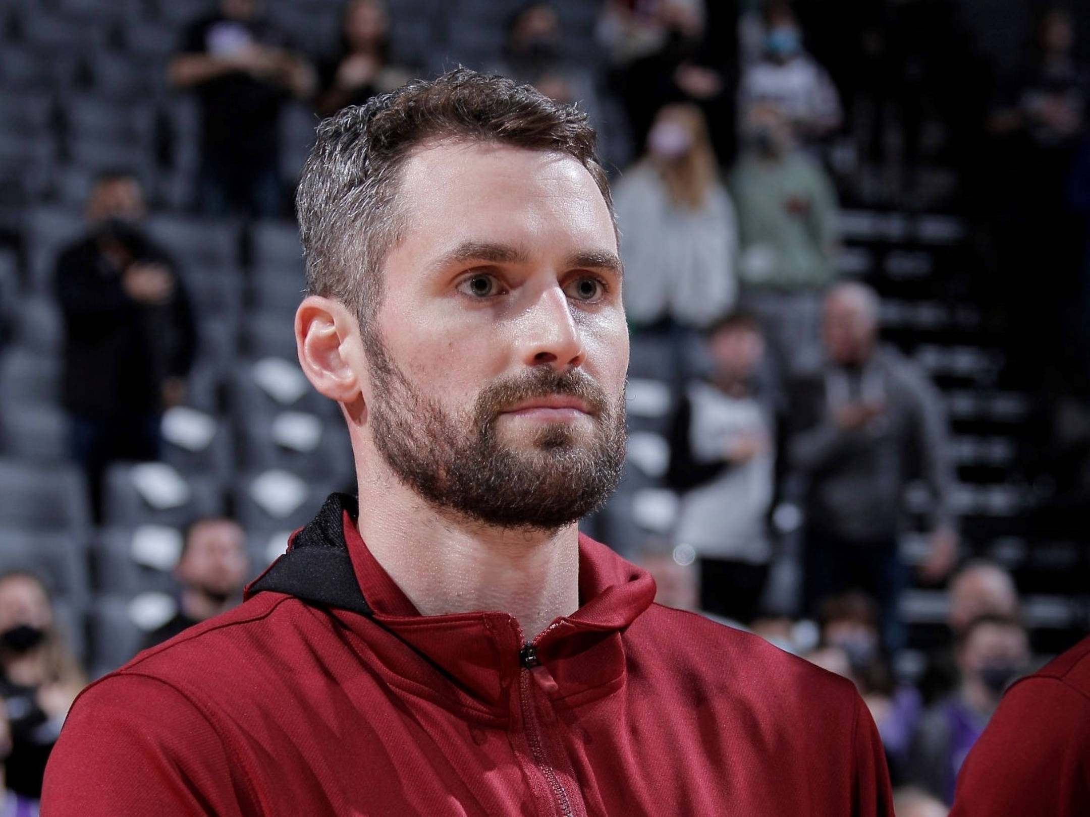 克里夫蘭騎士隊 Kevin Love 壁紙 — 一名身穿紅色連帽衫的專注籃球運動員在比賽中凝視著，背景是模糊的觀眾。
