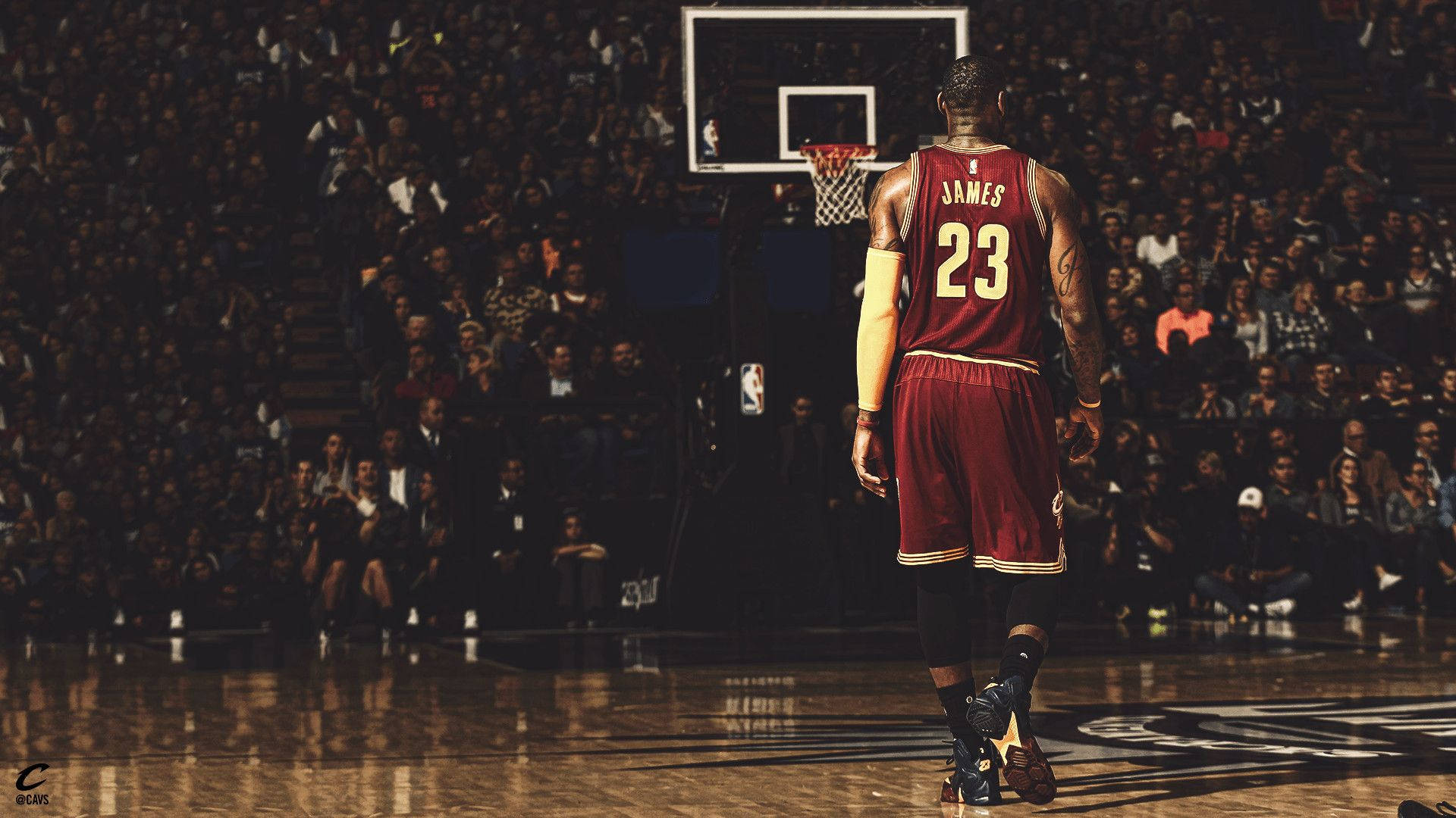 克里夫蘭騎士隊 勒布朗·詹姆斯在場上 壁紙 — 身穿栗色球衣的勒邦占士在場館燈光下走向籃框，觀眾在觀看。