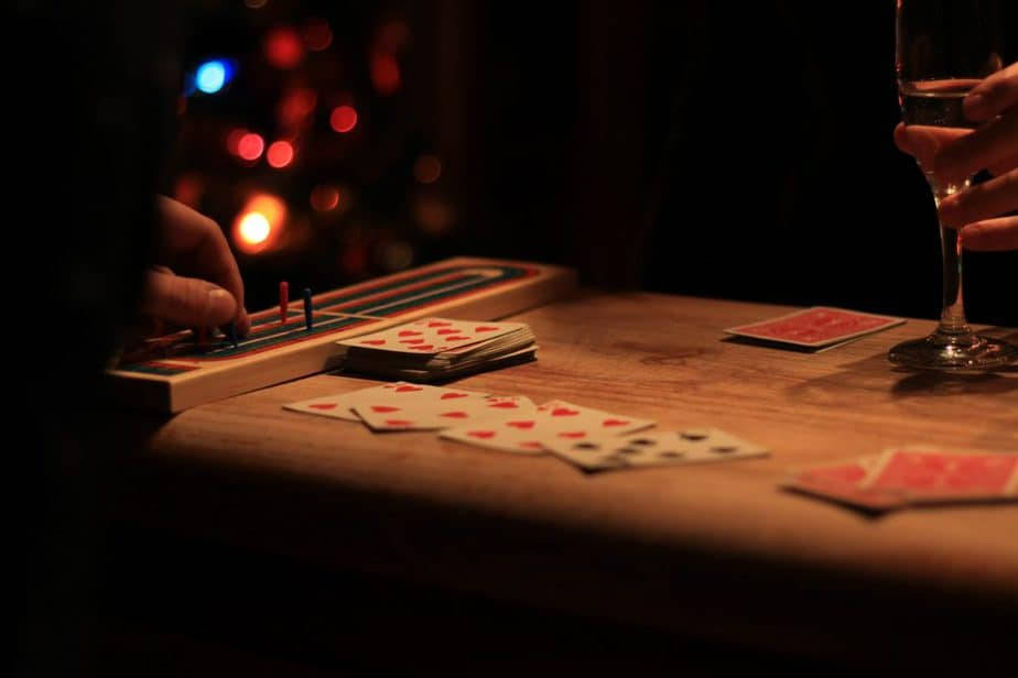 夜間在木桌上玩牌並移動遊戲棋子的雙手特寫。