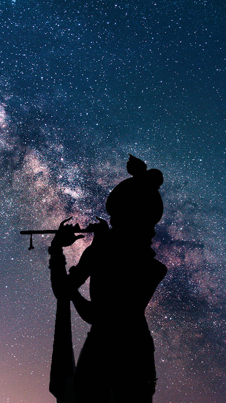 克里希那 iPhone 星空剪影 壁紙 — 吹笛者的剪影，背景是充滿活力的星空夜空，銀河在後方閃耀。