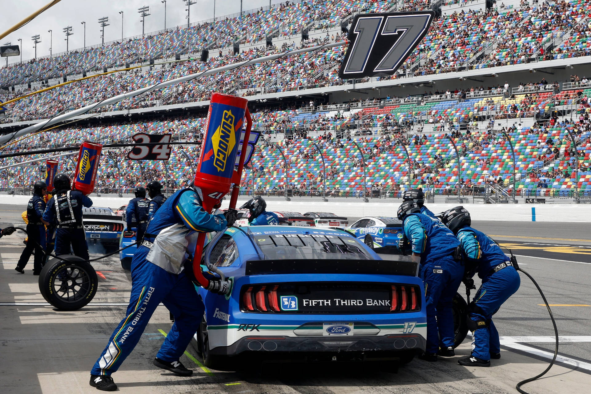 NASCAR維修站人員在日間比賽期間為藍色賽車更換輪胎。