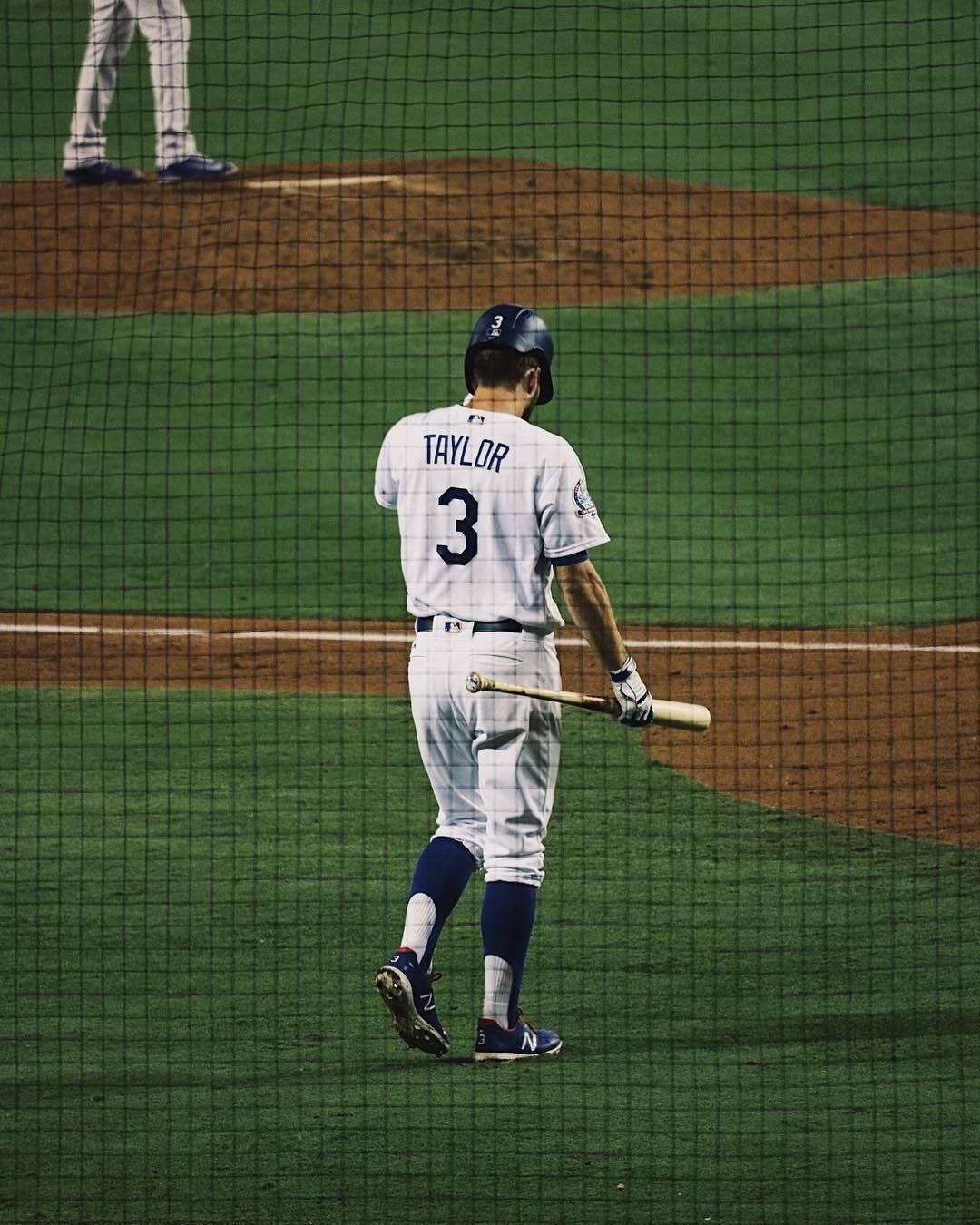 棒球手3號在夜間手持球棒離開本壘。