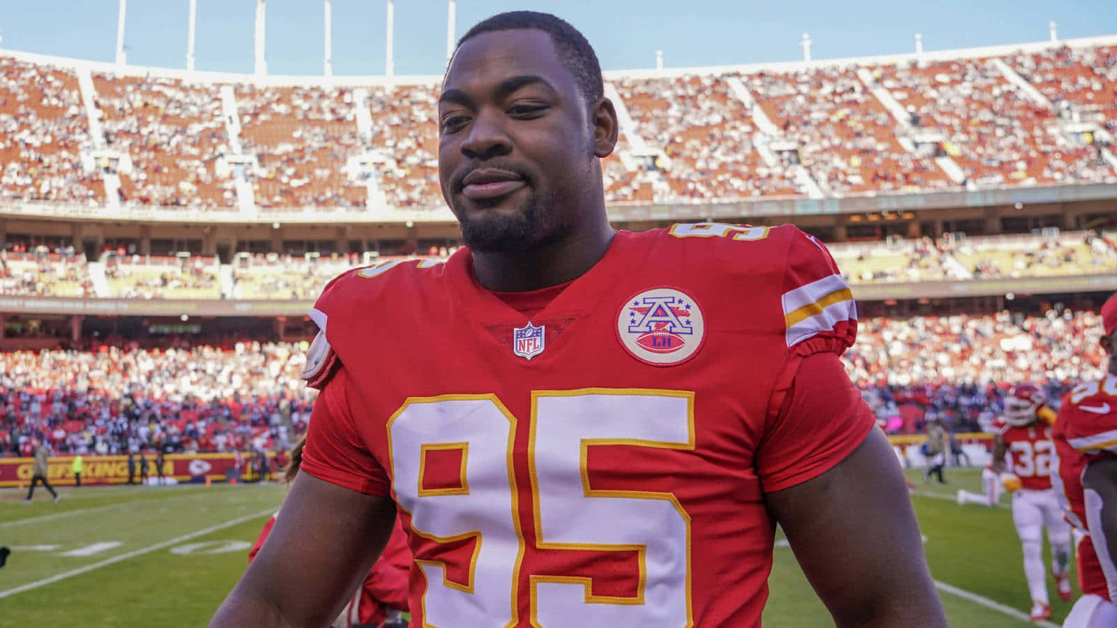 NFL美式足球運動員在陽光明媚的比賽日身穿紅色95號球衣。