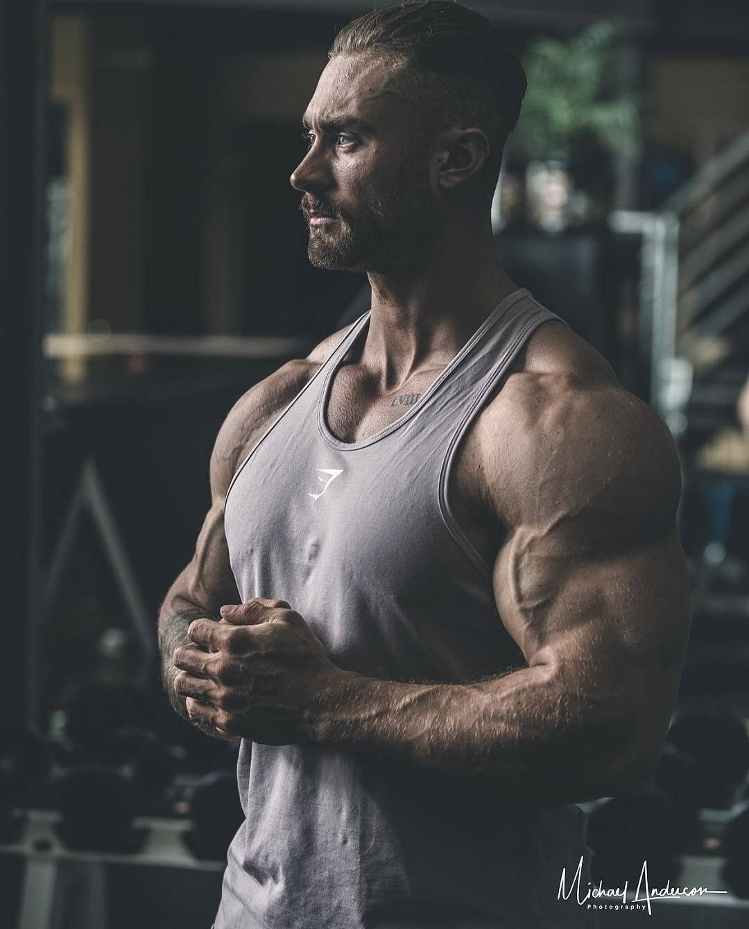 運動型男人，肌肉線條分明，在健身房穿著灰色背心站立