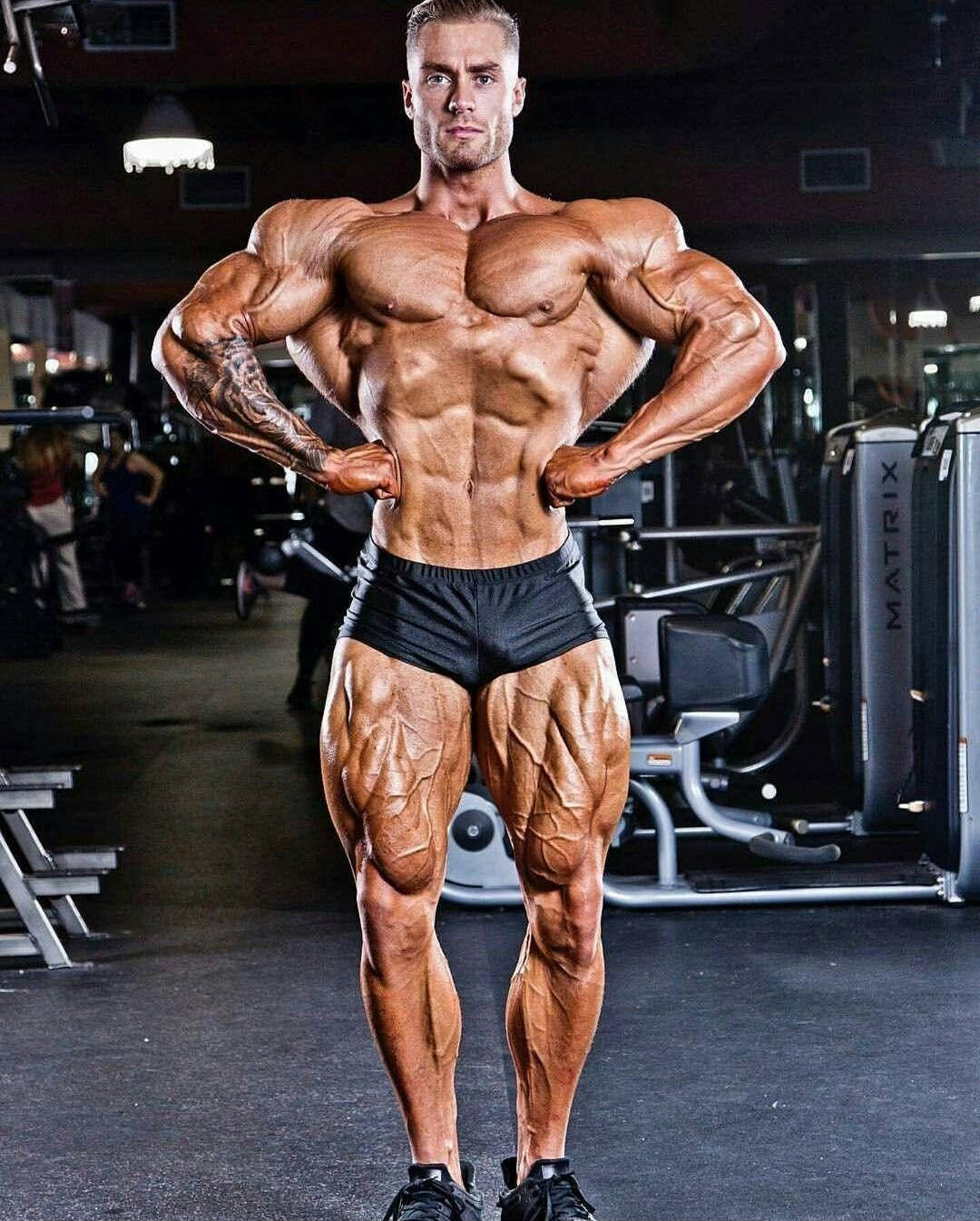 一位肌肉發達的男子在健身房展示清晰的肌肉和紋身。