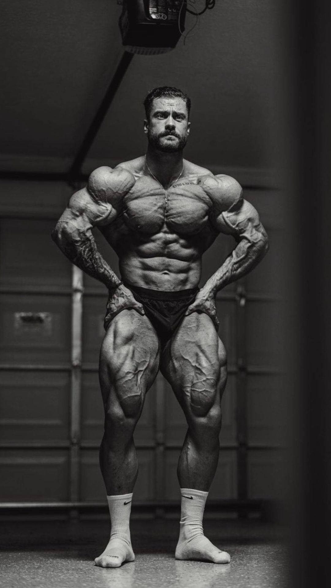 一位肌肉發達的男子在健身房中擺姿勢，擁有清晰的肌肉和紋身。