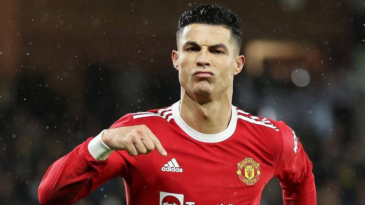Cristiano Ronaldo 身穿紅色曼聯球衣，在雨夜比賽中指向某處。