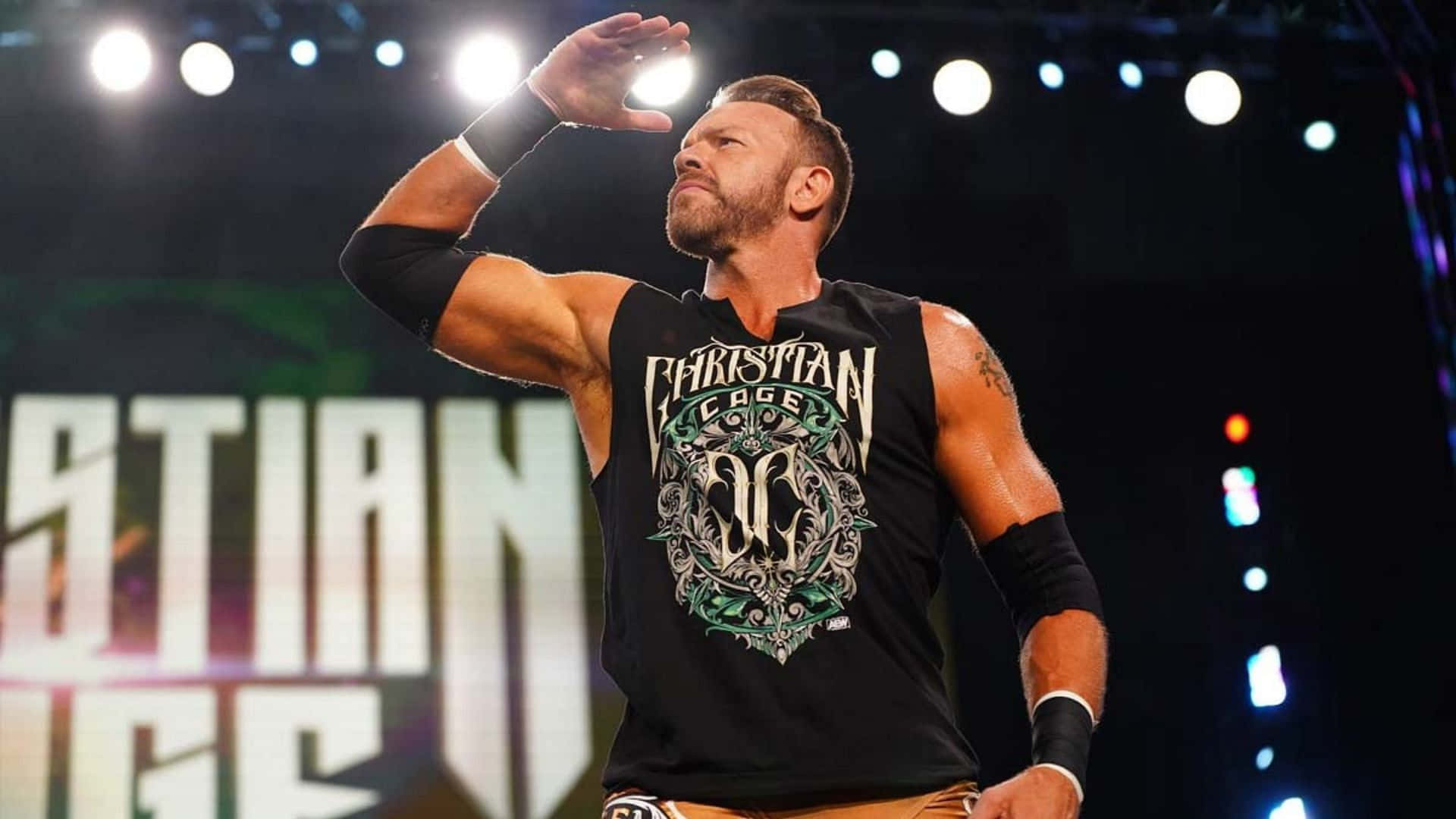 摔角手 Christian Cage 在場館燈光下向人群揮手。