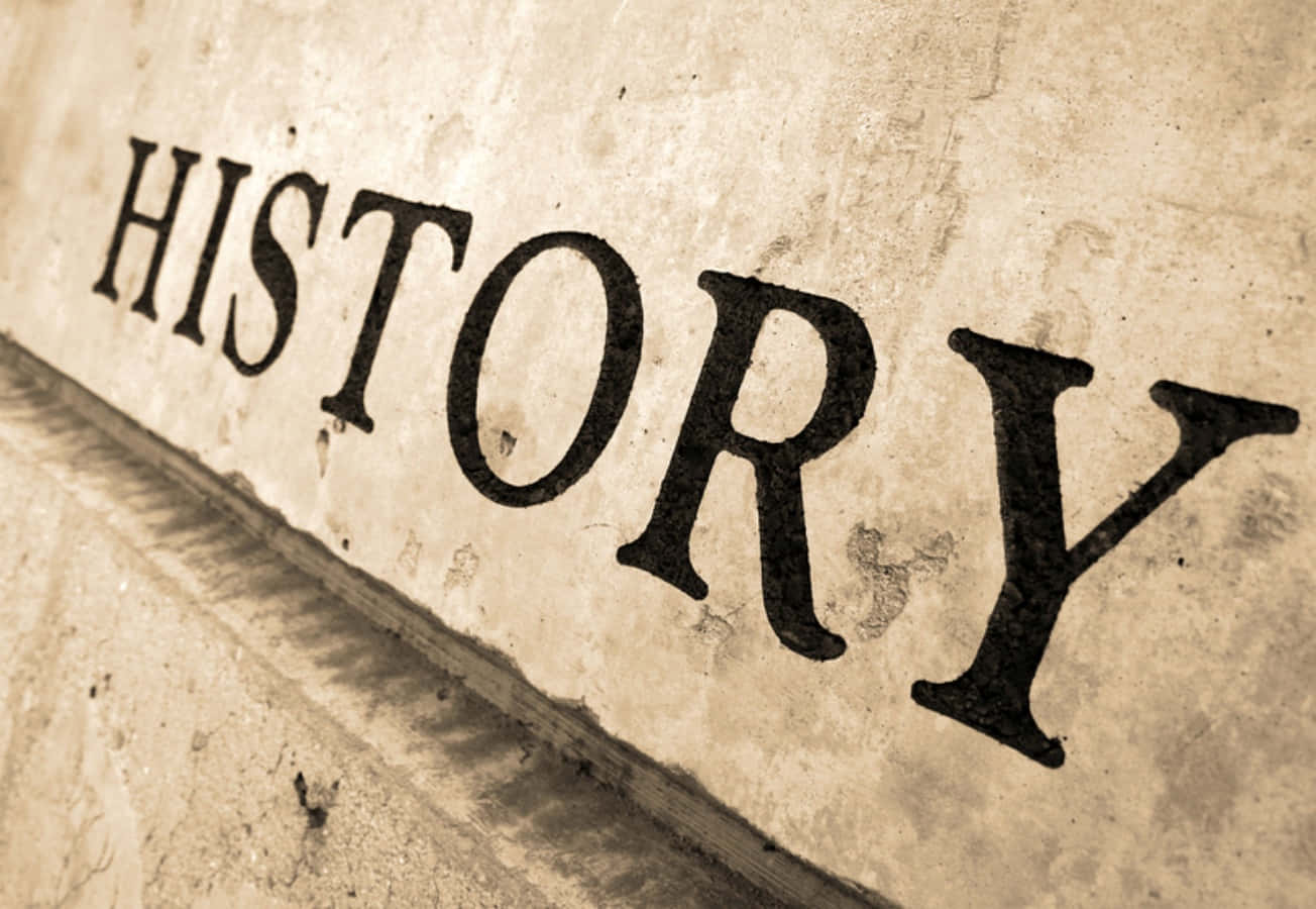「HISTORY」一詞的特寫，雕刻在帶有紋理表面的舊石上。