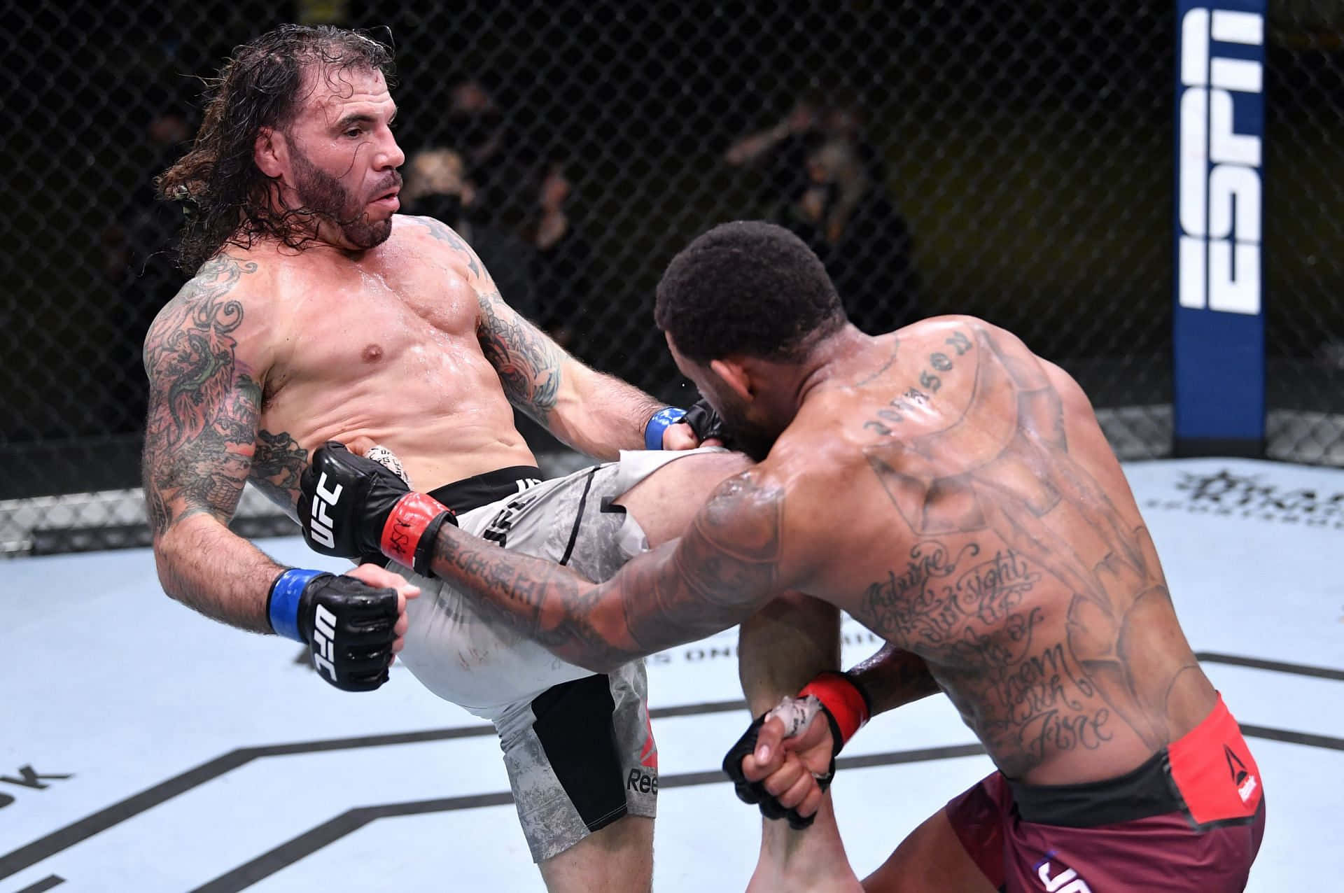克雷頓·吉達於UFC Fight Night 184 2021對戰邁克爾·約翰遜 壁紙 — 兩名紋身MMA拳手在UFC八角籠內激烈纏鬥，ESPN品牌標誌清晰可見。