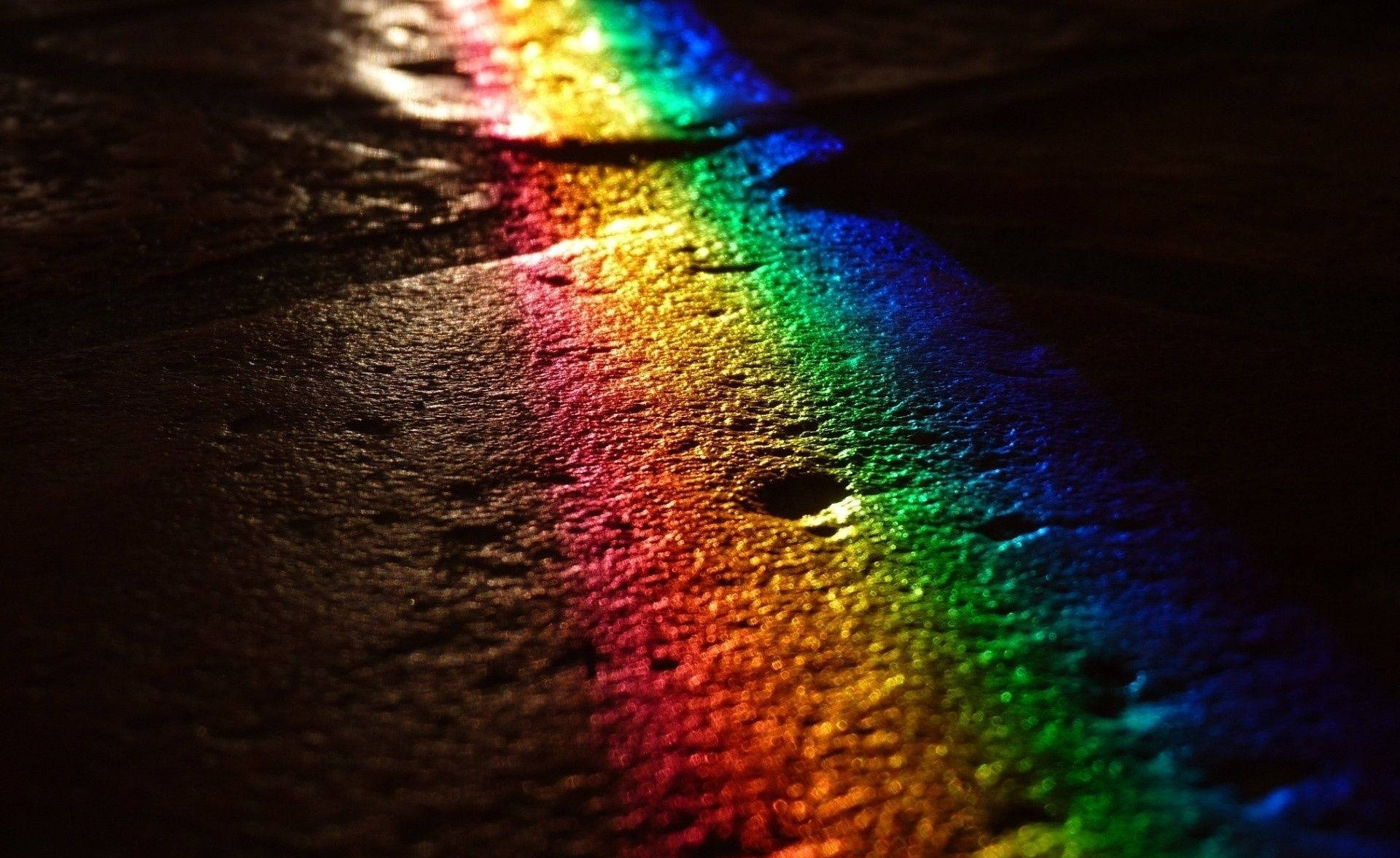 黑暗中潮濕路面上的彩虹光反射