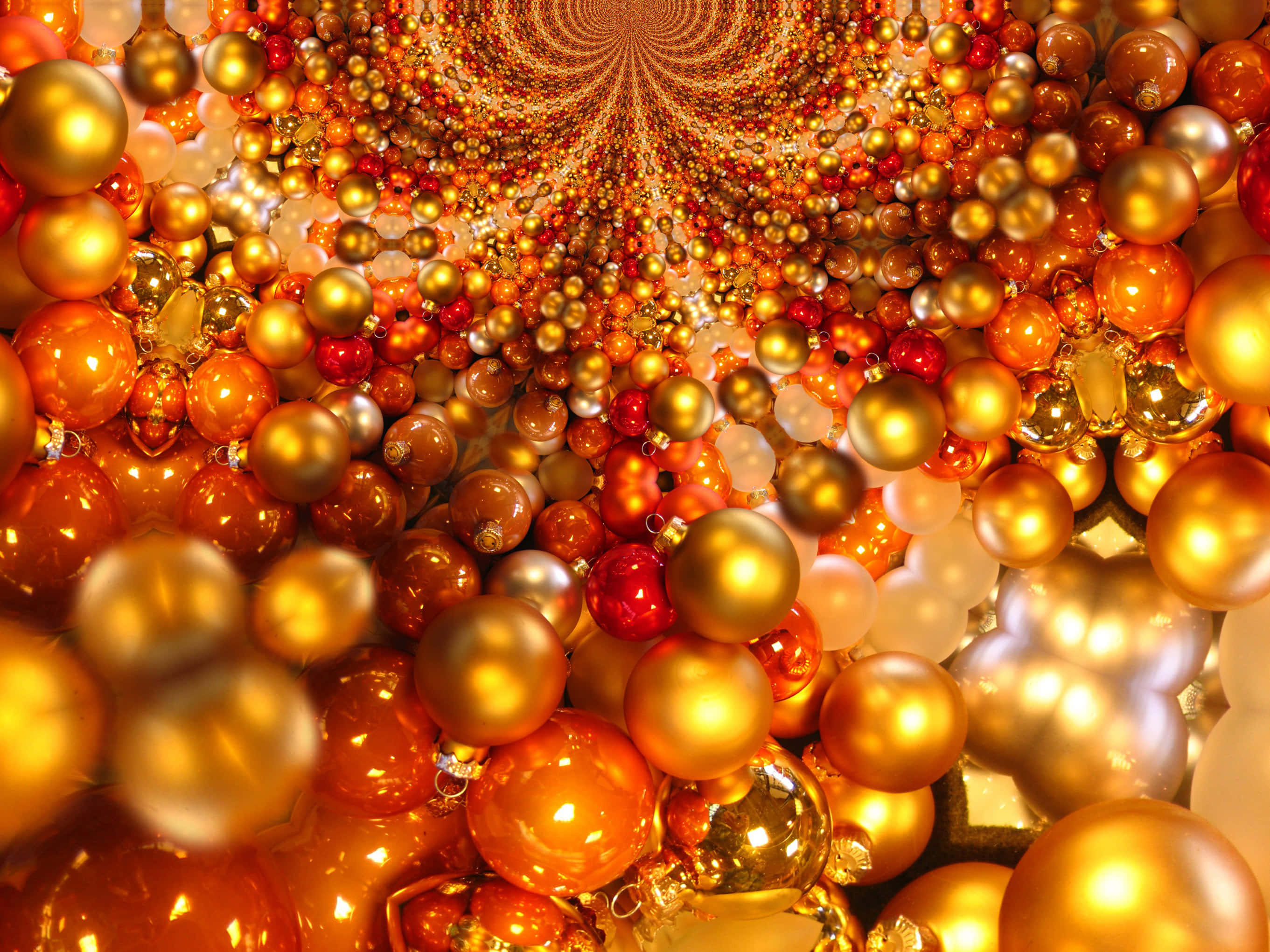 免費紅金聖誕球圖片 壁紙 — 由無數金色、橙色、紅色和白色的反光聖誕裝飾形成的迷人螺旋隧道，營造出節日的萬花筒效果。