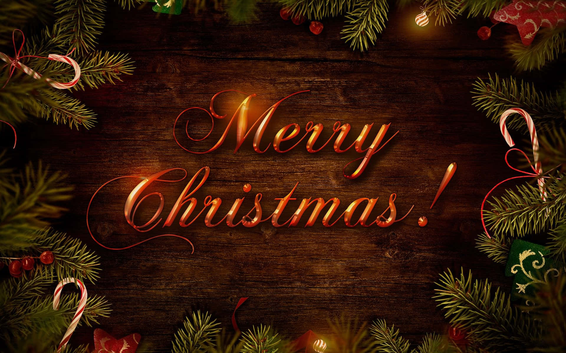 免費聖誕節問候圖 壁紙 — 金色草書 Merry Christmas 文字在由松樹枝、拐杖糖和節日裝飾品框住的質樸木質背景上溫暖地發光。