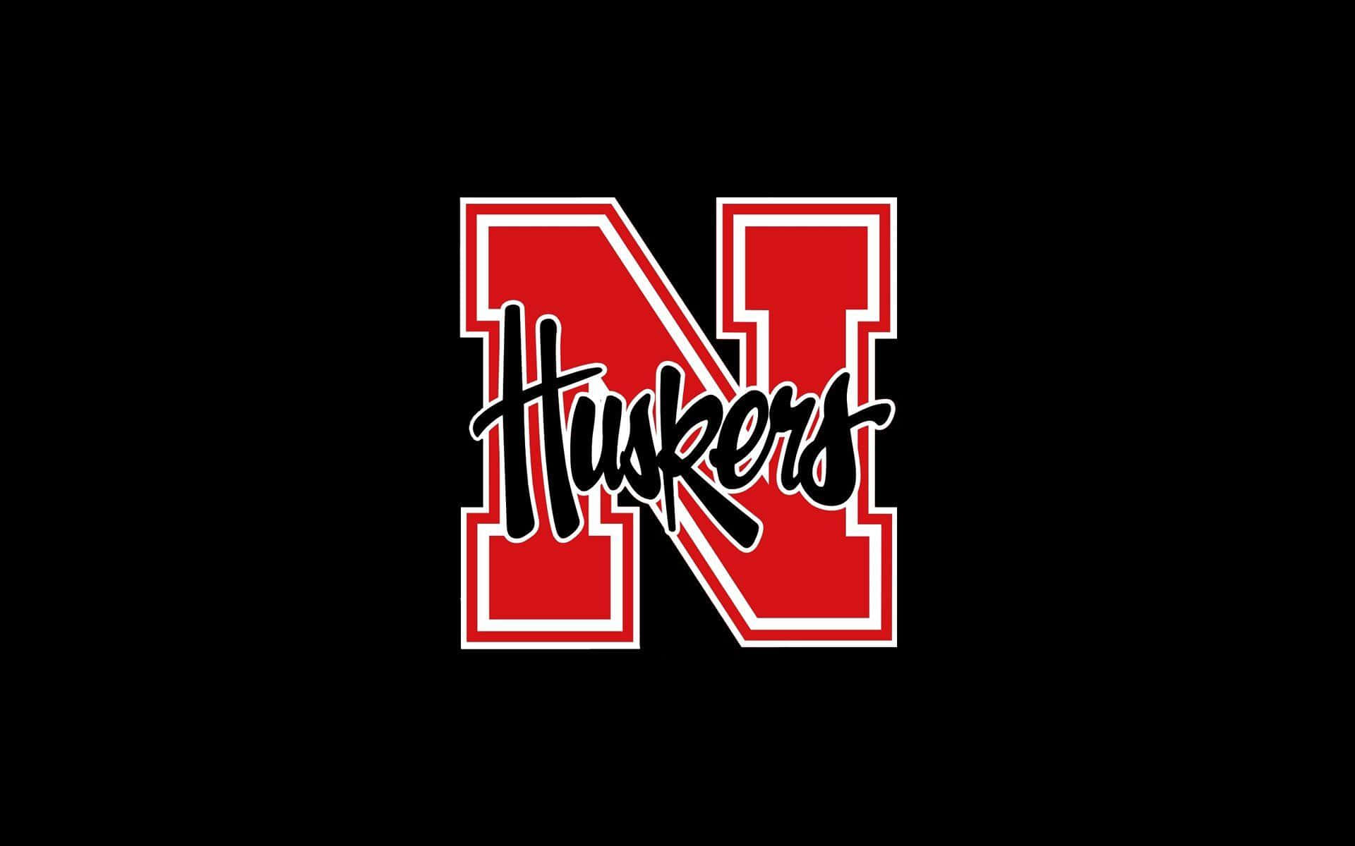 內布拉斯加紅衣隊足球的熱情氛圍 壁紙 — 大膽的紅黑 Huskers 標誌，帶有白色輪廓，居中在純黑色背景上。