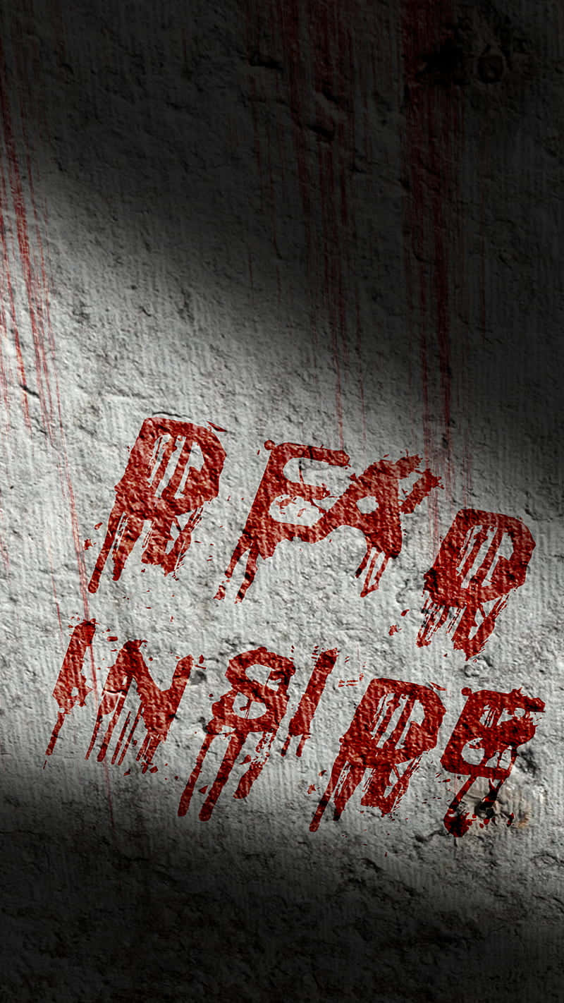 在聚光燈下粗糙的混凝土牆上，血紅色塗鴉寫著 fear inside。