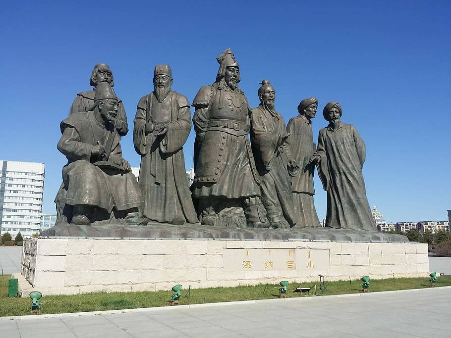 內蒙古的成吉思汗雕像 壁紙 — 一座大型銅像，描繪六位身穿傳統長袍的歷史人物，在晴朗藍天下傲然矗立於開闊廣場。