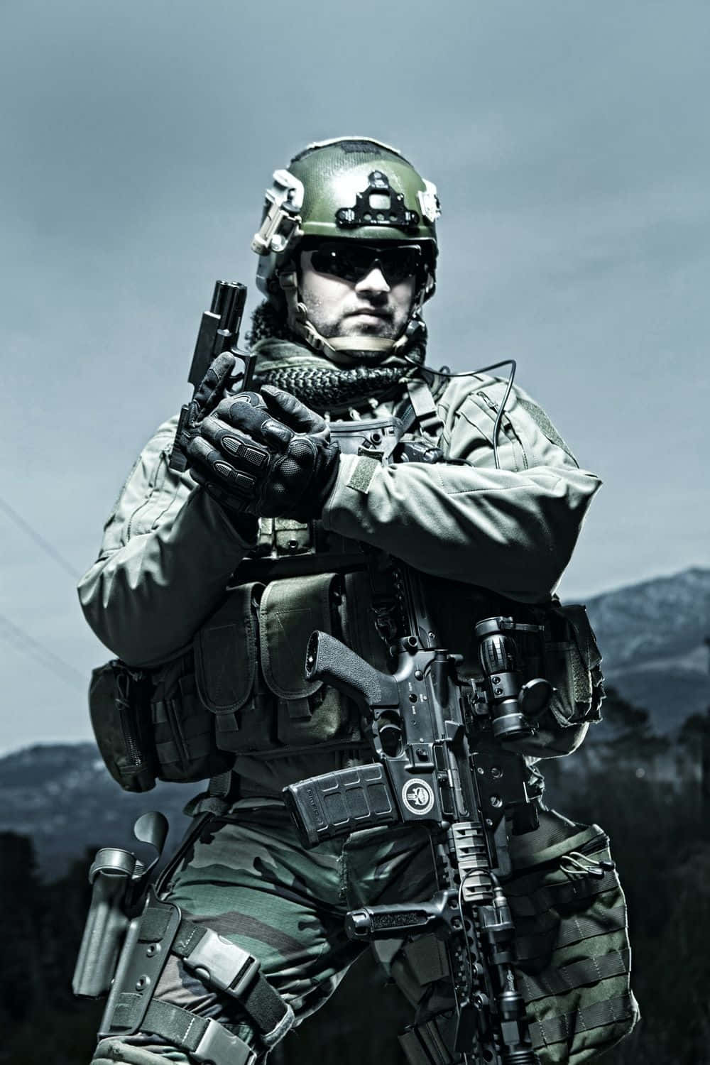 全副軍裝的軍人 壁紙 — 一名身穿全套戰術裝備的士兵，在戶外手持手槍，背景是山脈。